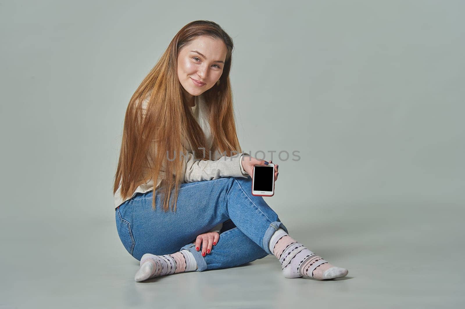 A girl sits in the background with a phone in her hands and smiles. High quality photo