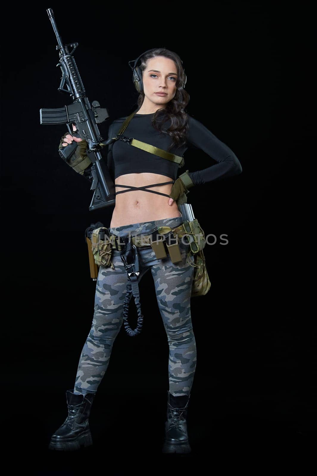 a young woman with a rifle stands on a black background. High quality photo