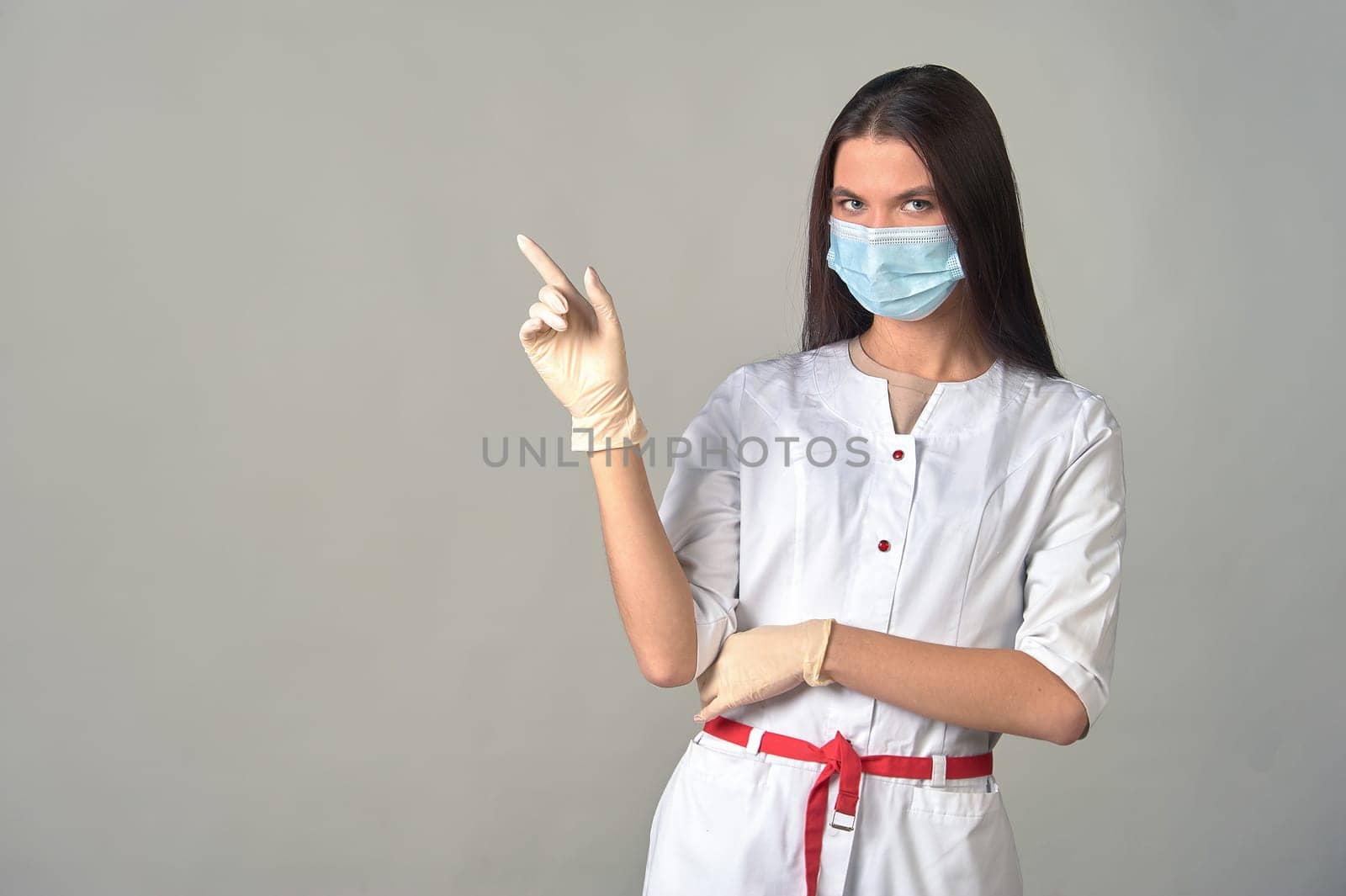an attentive female doctor in a medical gown, mask and gloves, warning about something important. . High quality photo