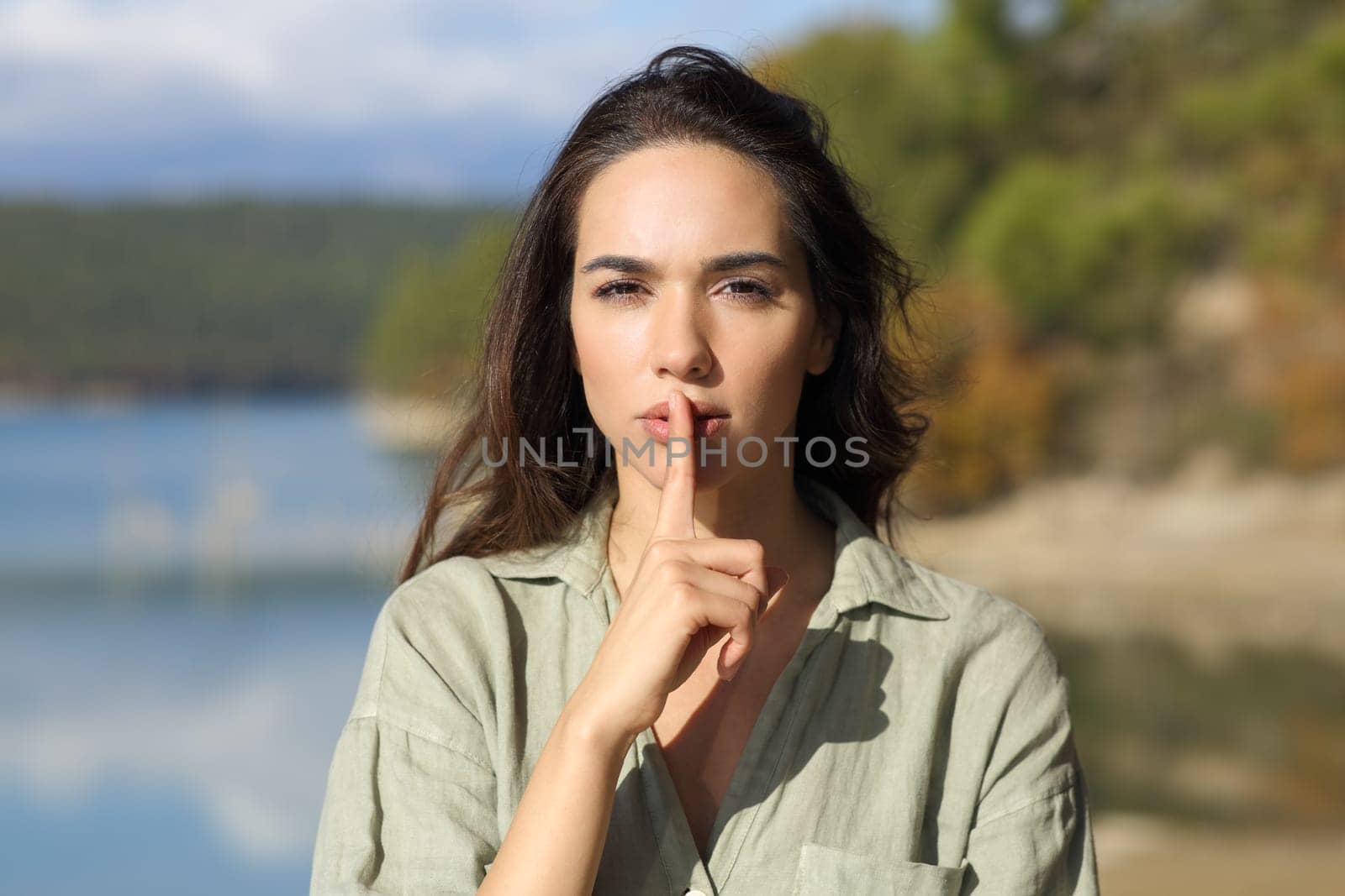 Front view portrait of a serious woman asking for silence in a lake