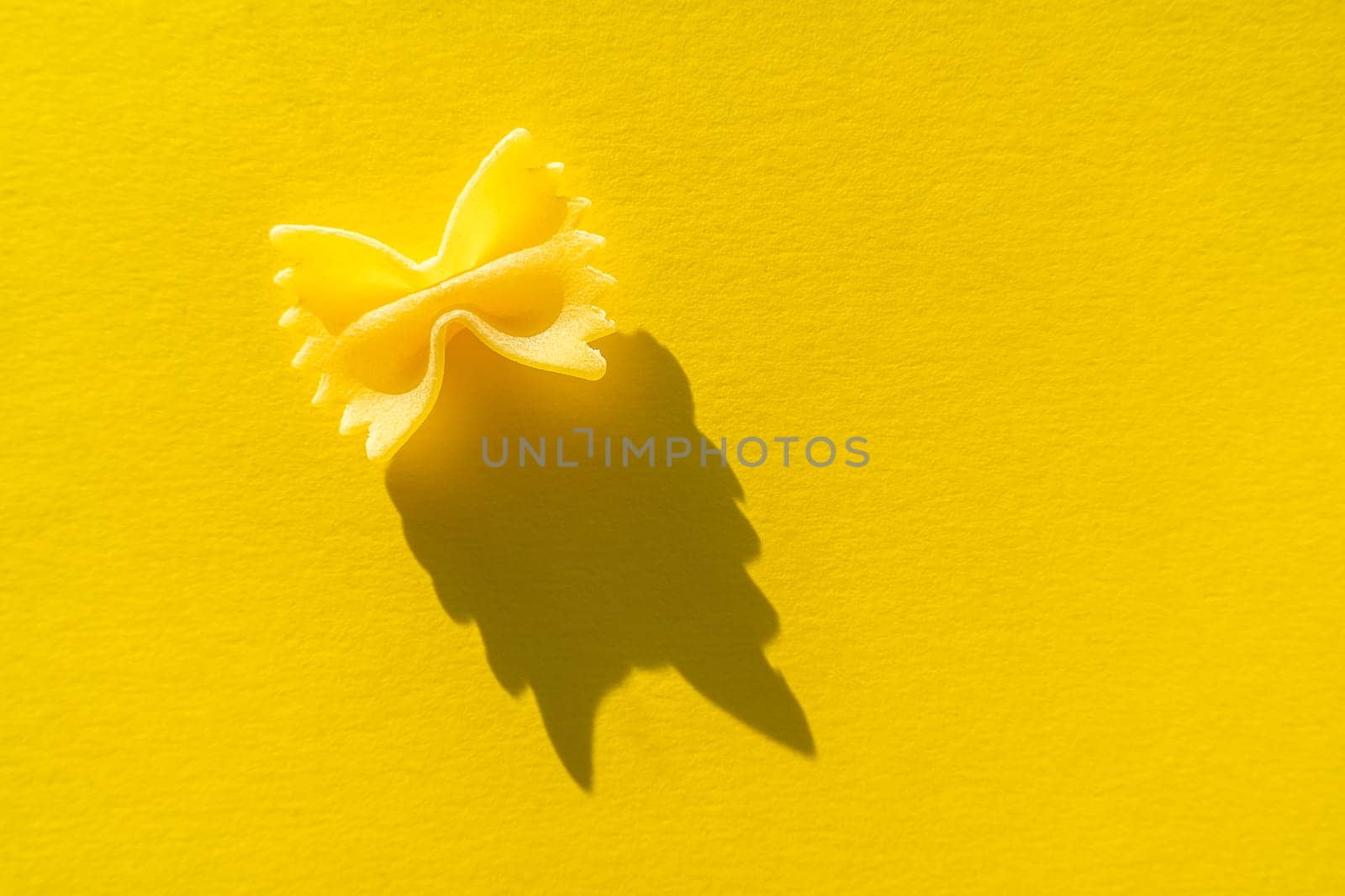 Close-up of farfalle. paste on a yellow background in bright light