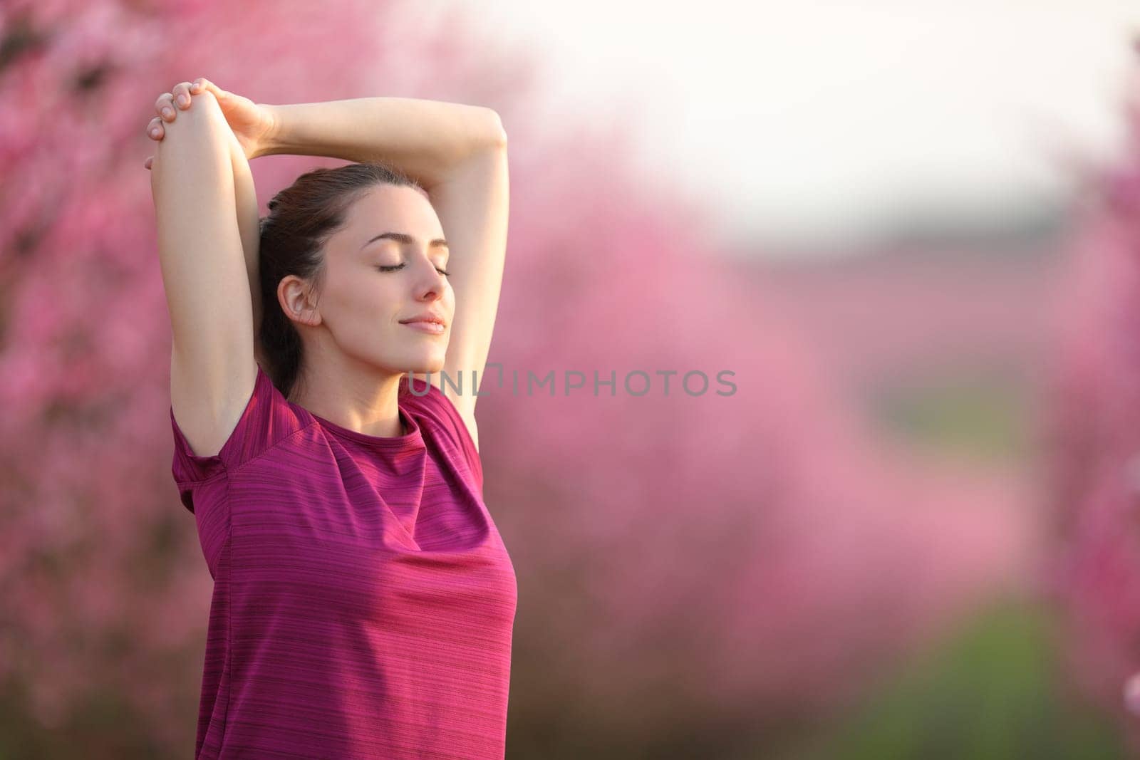 Sportswoman stretching arms and relaxing in a field after sport