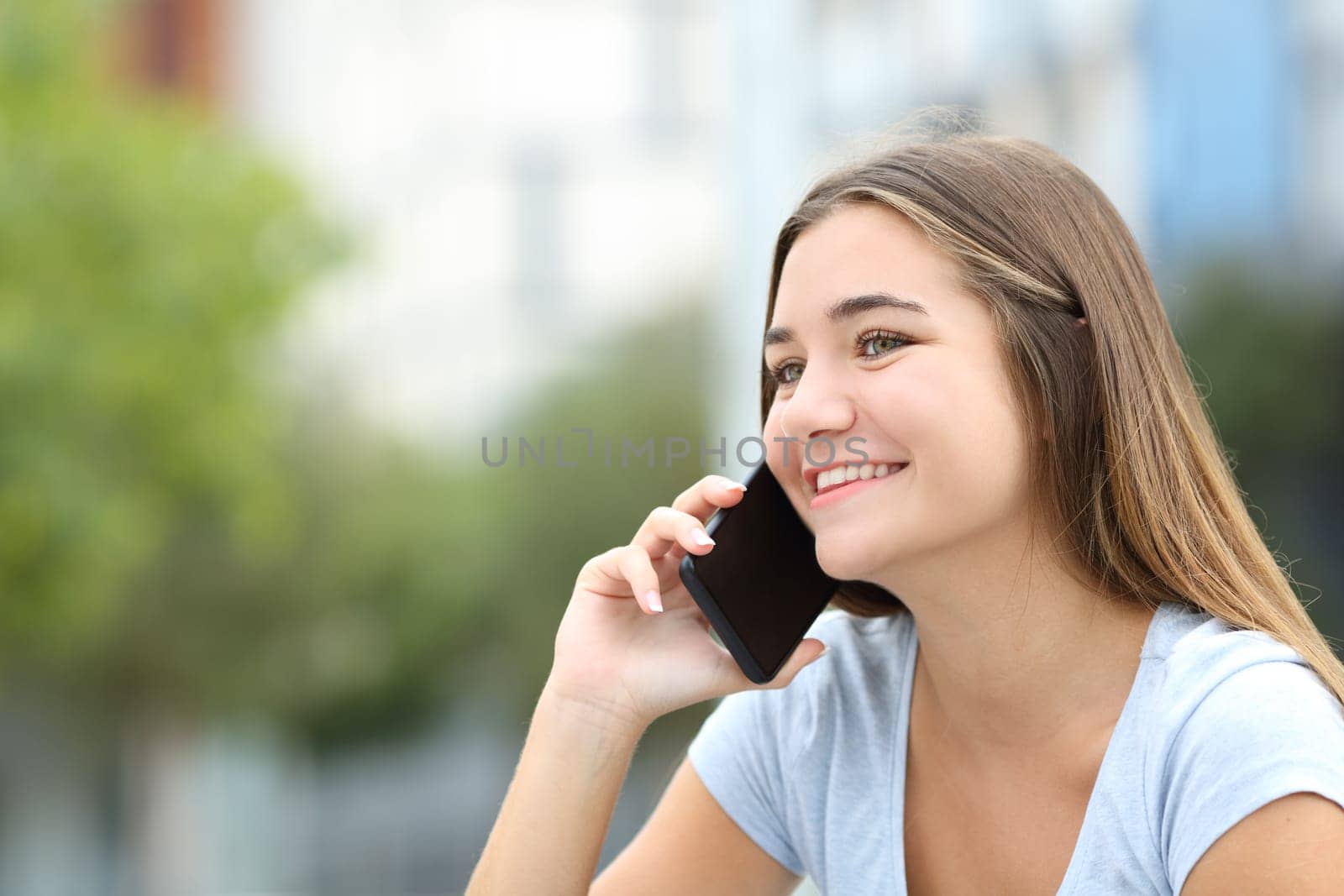 Happy teen talking on mobile phone in the street