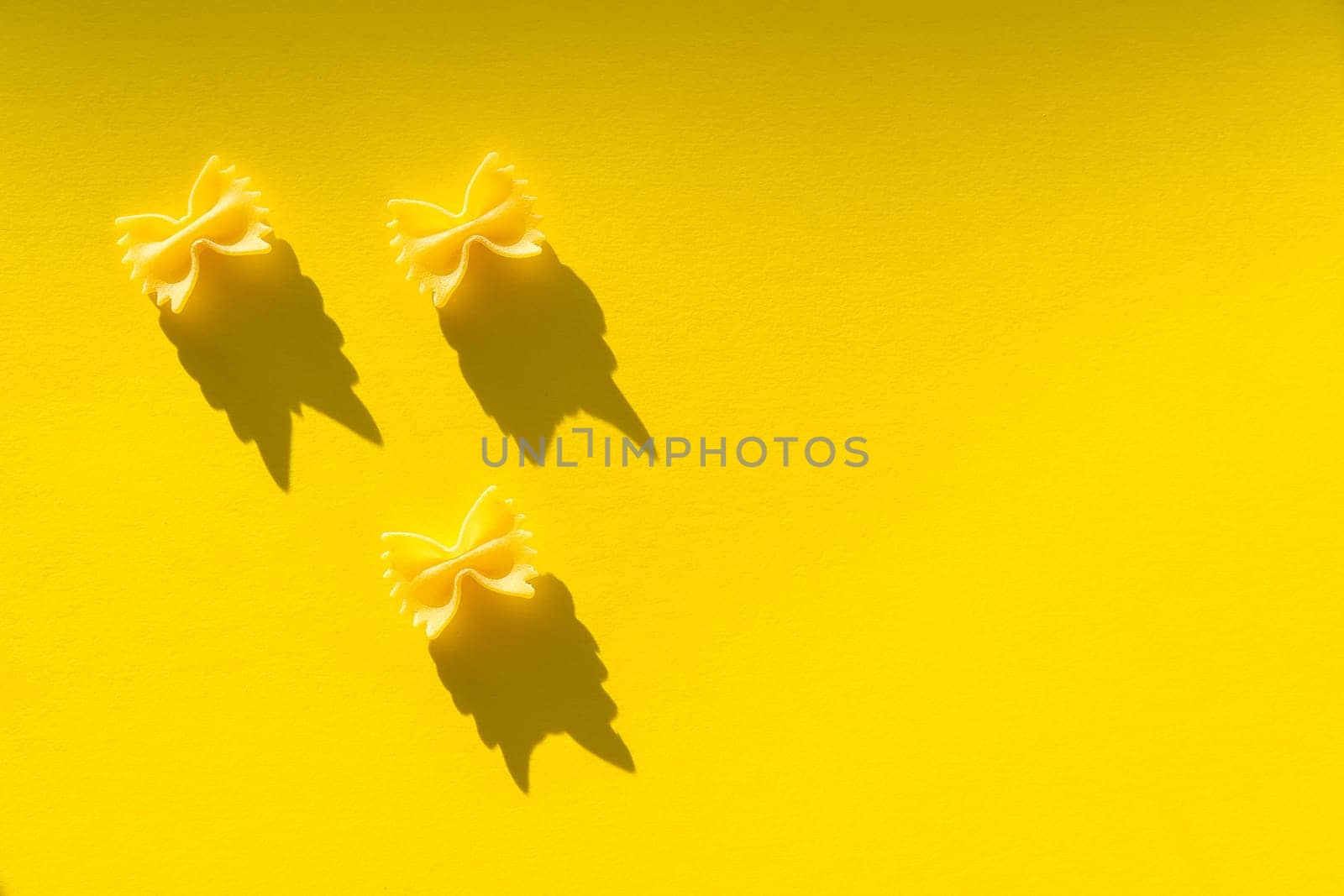 Three pieces of farfalle paste on a yellow background.