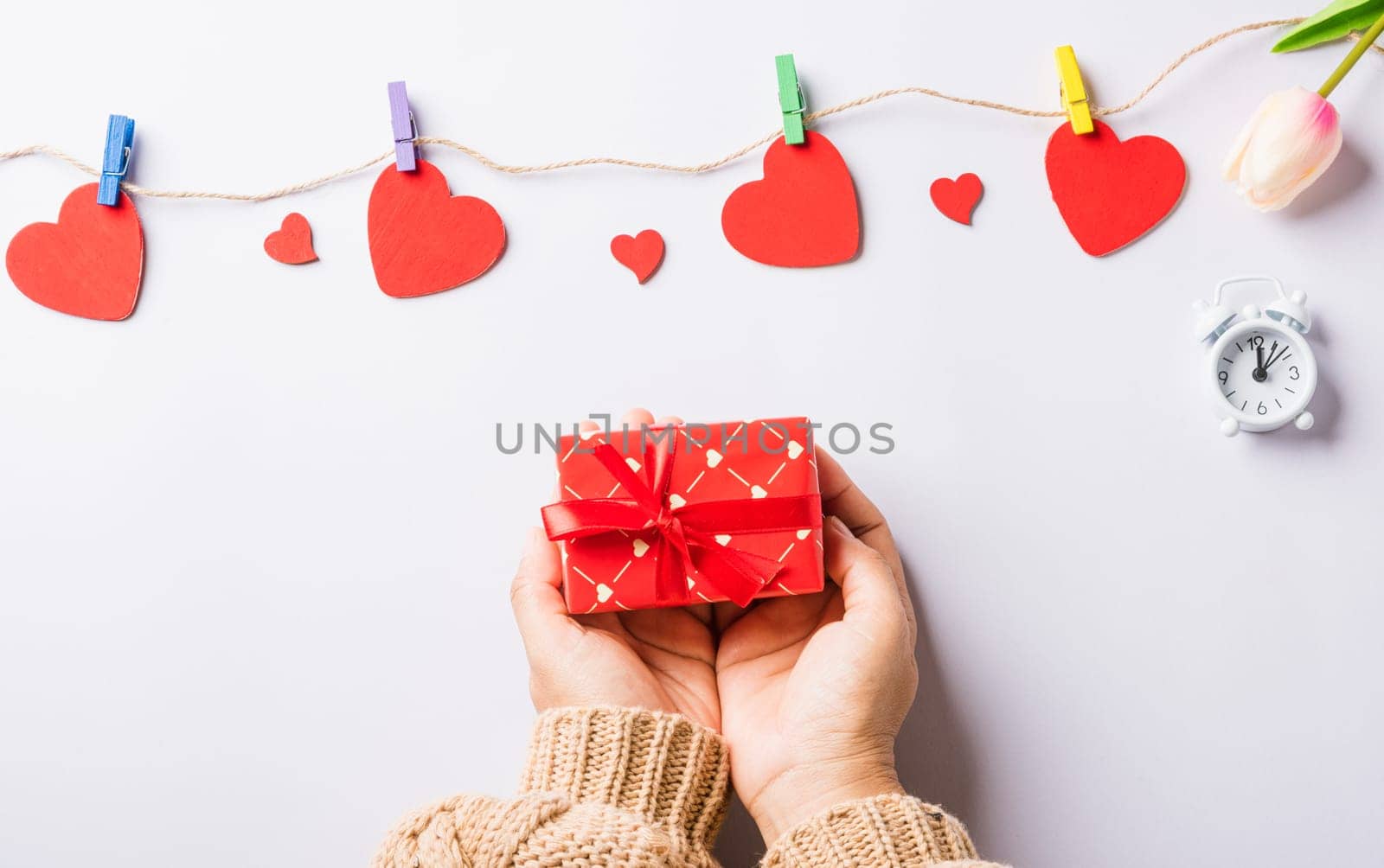 Valentine's day and birthday. Woman hands holding gift or present box decorated and red heart surprise on white background, Female's hand hold gift box package in craft paper Top view flat lay