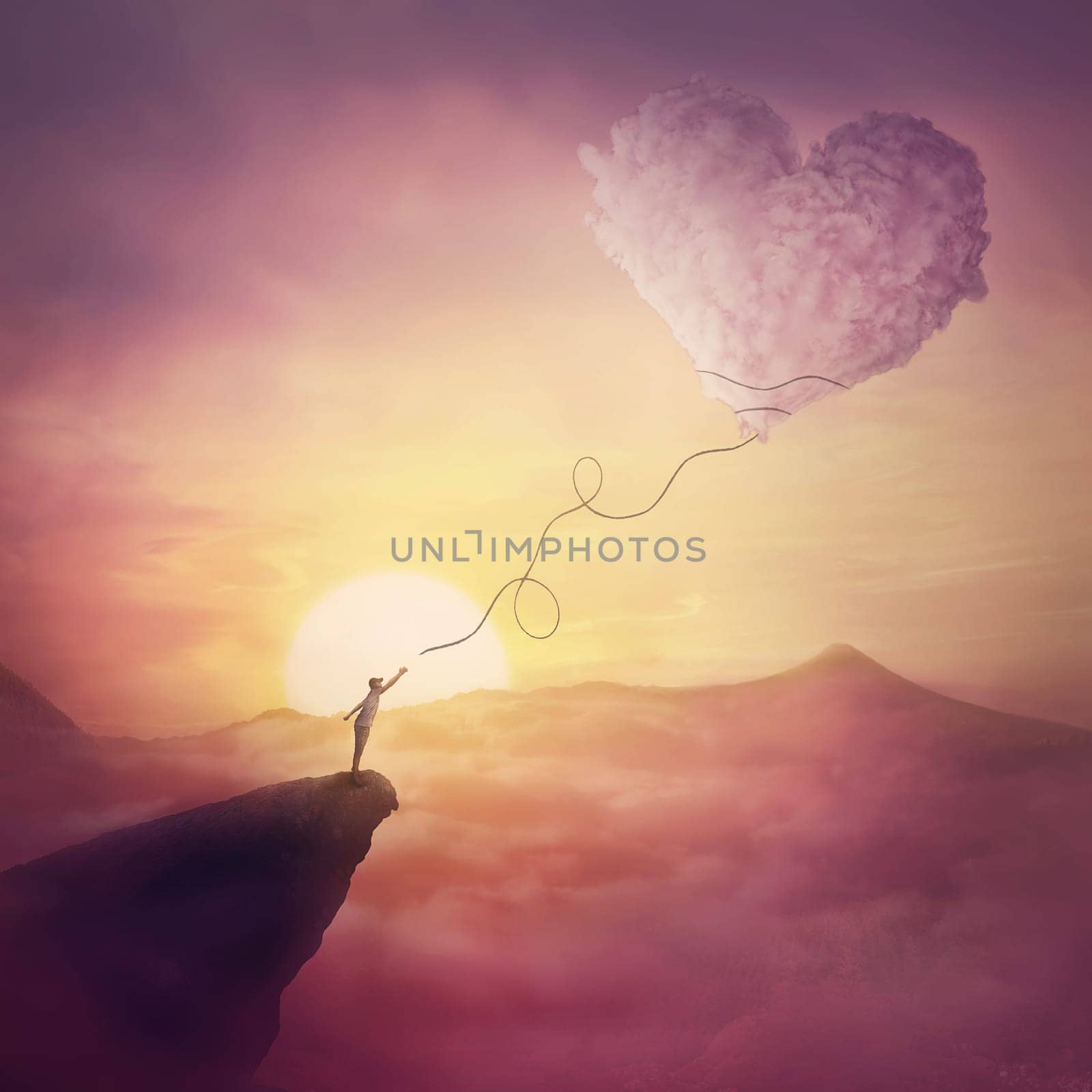 A person on the cliff and a heart shaped cloud like a kite raising up in the air. Magical scene, love and romance concept. Pink sunset clouds, peaceful view