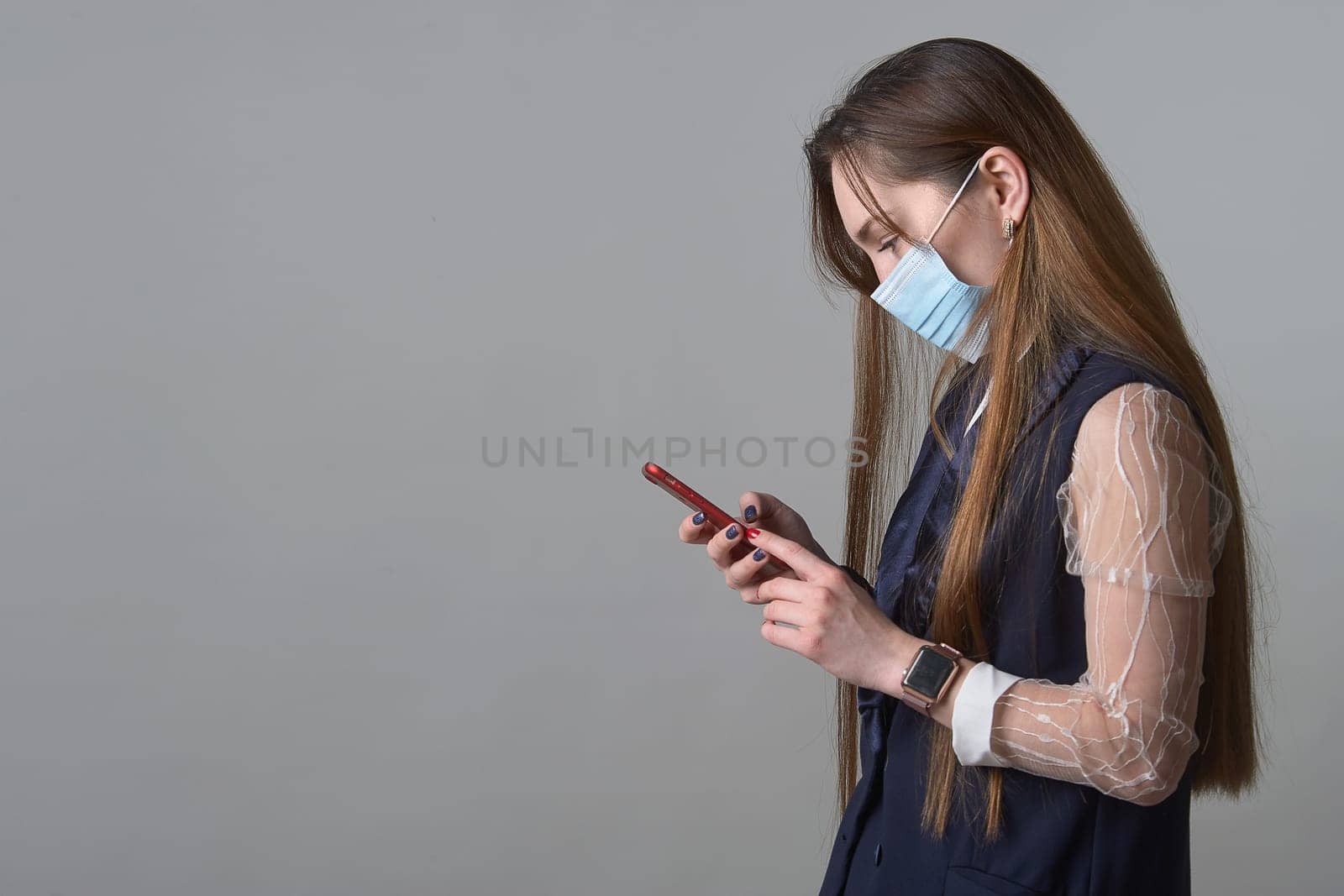 A girl in a medical mask with a phone in her hands. High quality photo