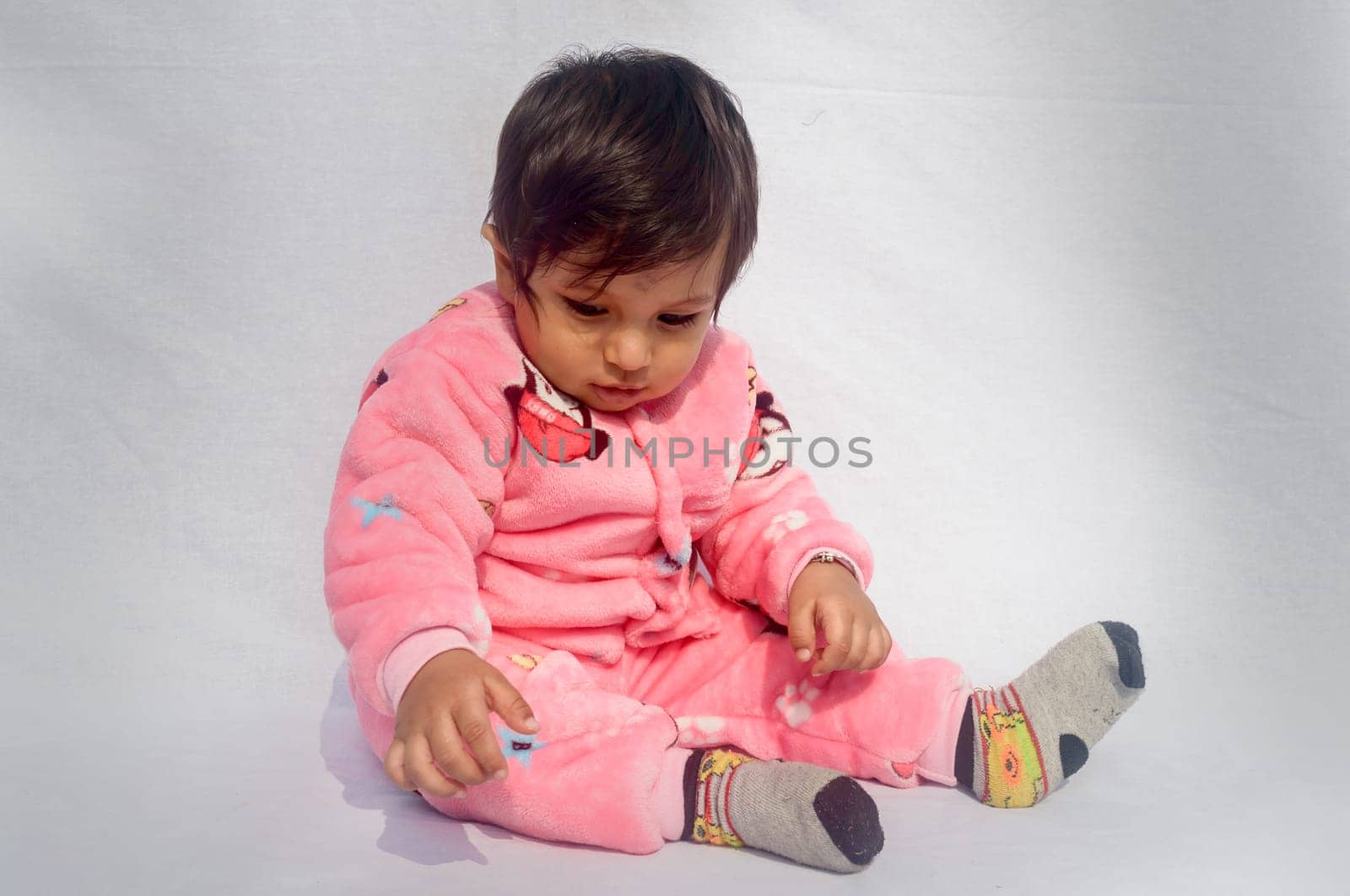 Close-up Portrait of happy Baby Wearing pink Velvet warm clothes on white background. Cute Baby in Bodysuit Autumn or winter fashion Outfit on a sunny day. Pretty little boy. Copy space. Front View