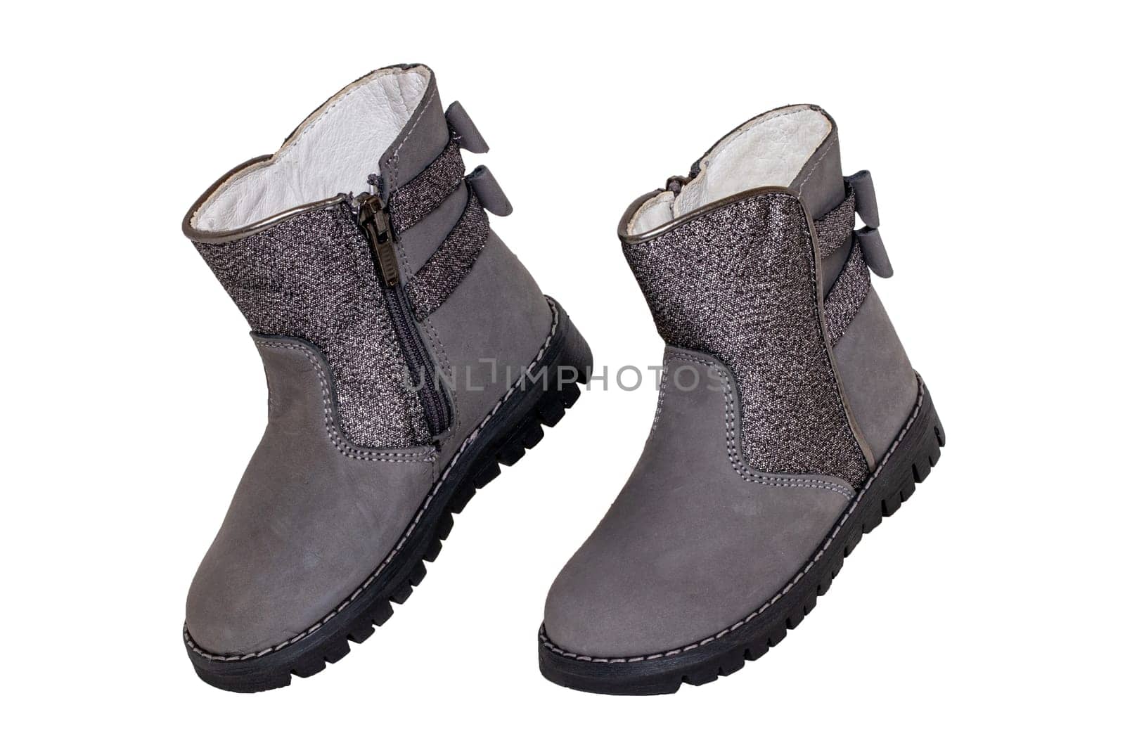 Winter boots. Close-up of a pair elegant gray silver leather winter boots lined with white leather. Girls winter shoe fashion new trends isolated on a white background. Macro photograph.