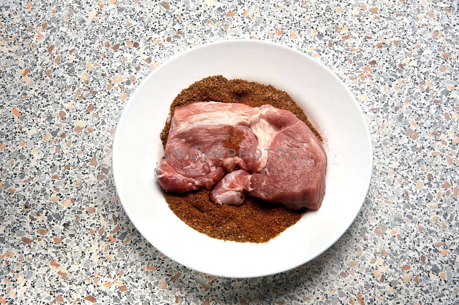A piece of spiced meat in a plate before frying. High quality photo
