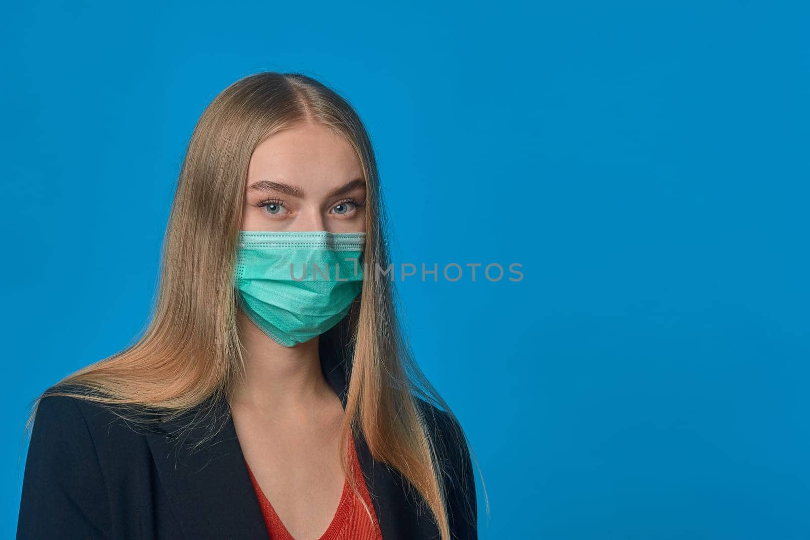 Portrait of a girl in a medical mask on a blue background. High quality photo