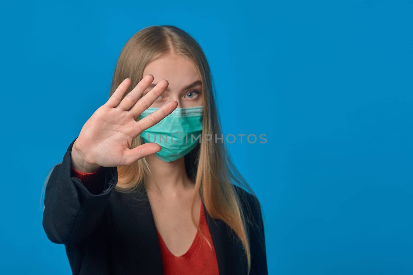 A girl in a medical mask shows her hand stop. High quality photo