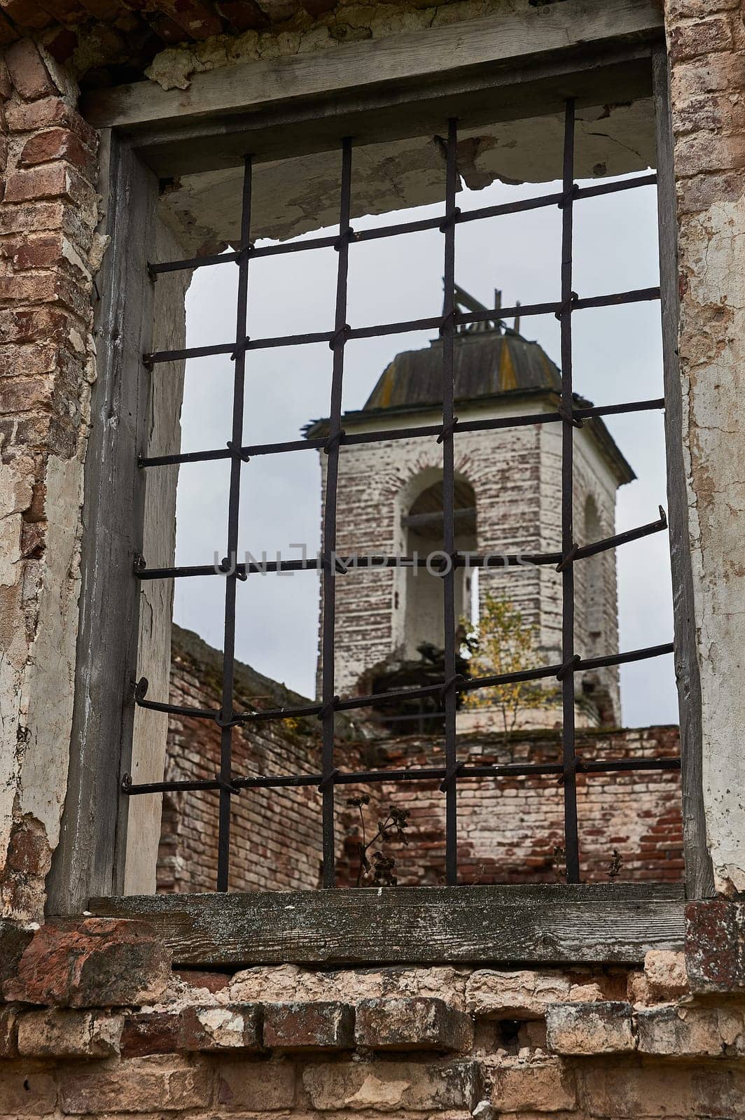 View of the ruined bell tower through a window with bars. High quality photo