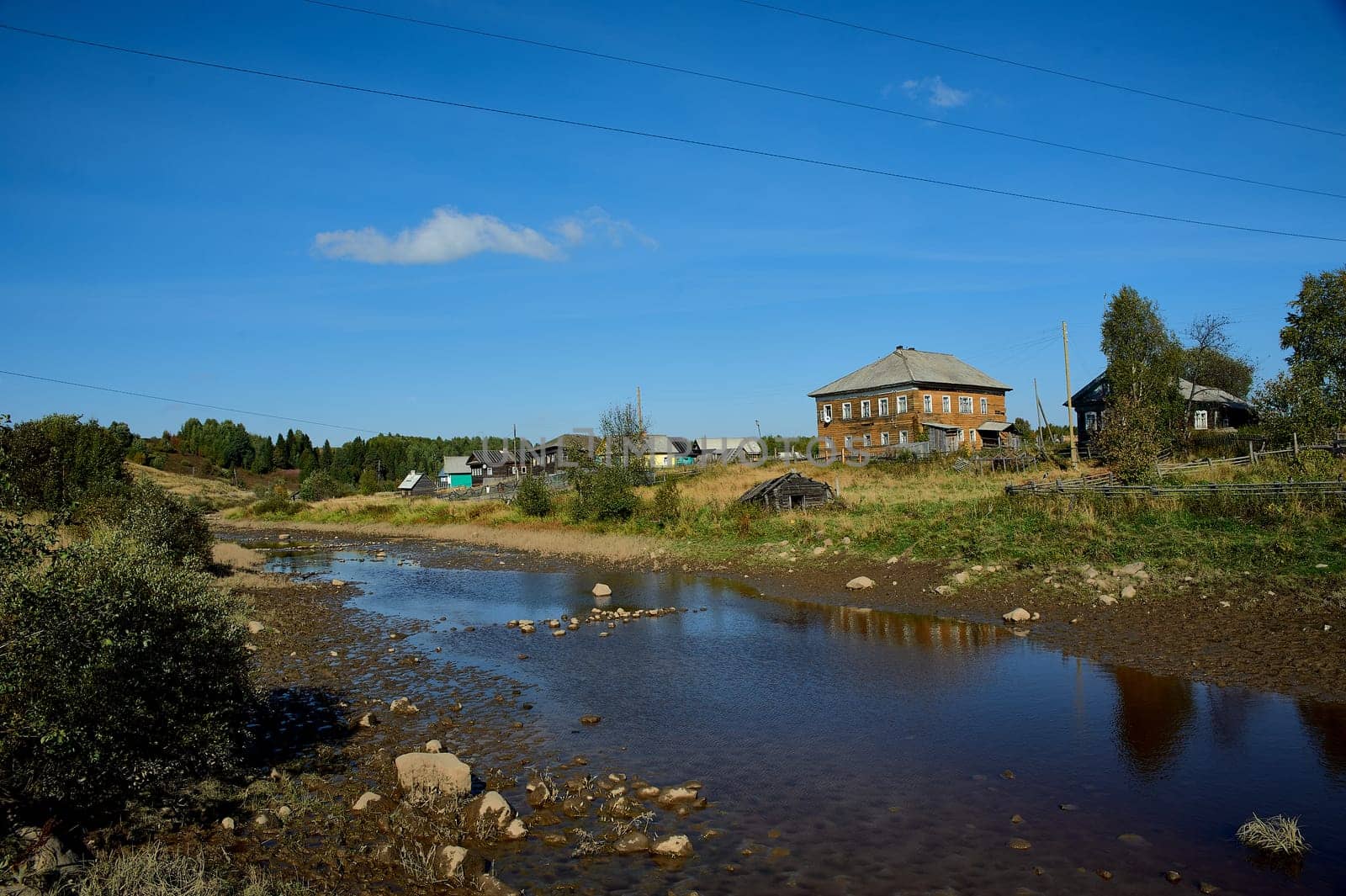 Shallow river on the background of the village. High quality photo