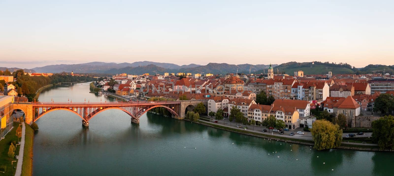 Panoramic view of Maribor city in summer at sunrise from above. Historical city in Slovenia with space for text. Bridge with river in morning sunlight.