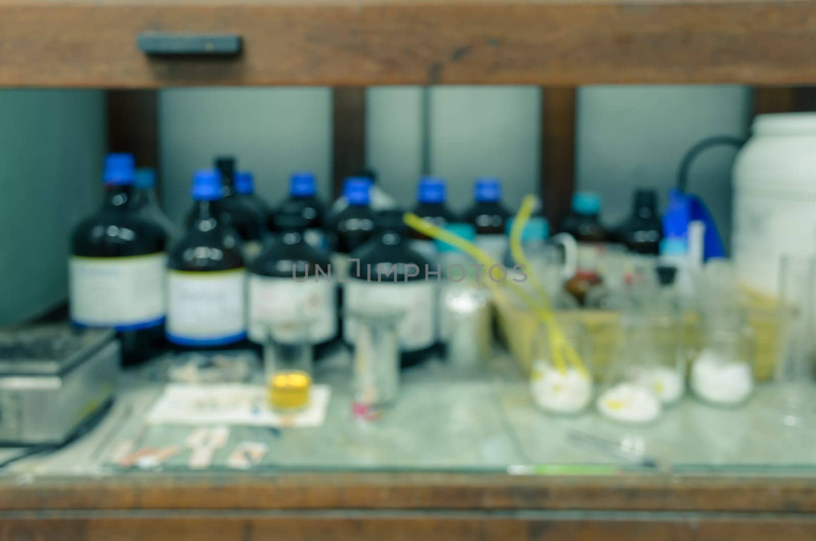 Blurred abstract background of old wooden chemical hood with reagent bottles in laboratory
