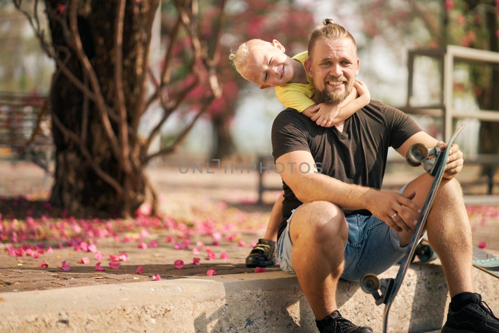 Father is having fun together with his little son in skate park Springtime. Portrait