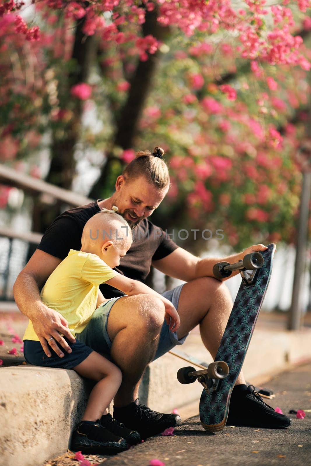 Father is hugging his little son in skate park. Springtime. Real family. Spending quality time together
