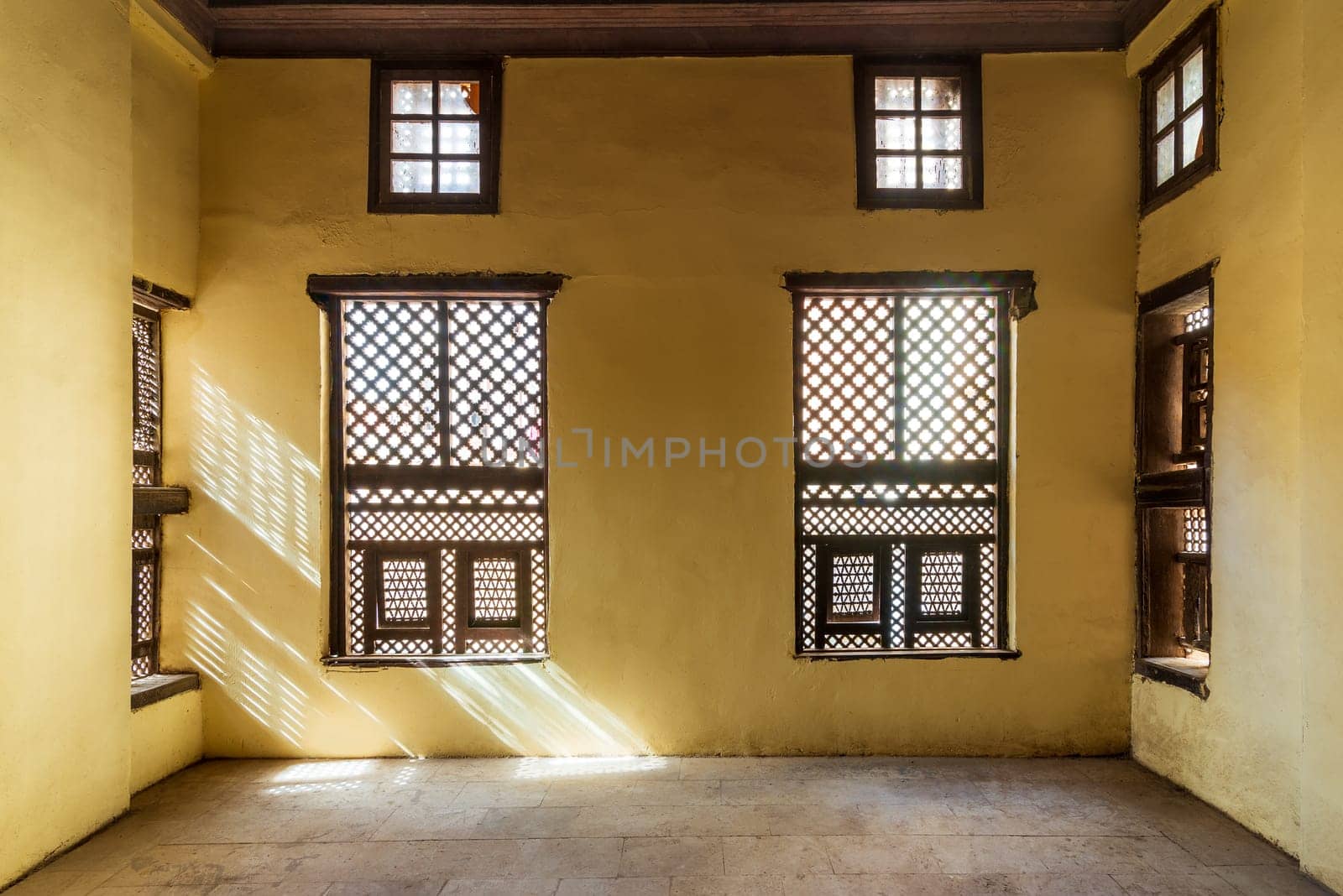 Facade of two Interleaved grunge wooden ornate windows - Mashrabiya - in stone wall in abandoned building