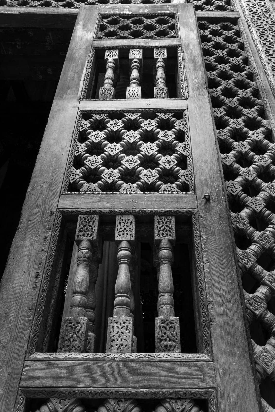 Black and white angle view of wooden carved decorations of interleaved wooden door - Mashrabiya - in abandoned building