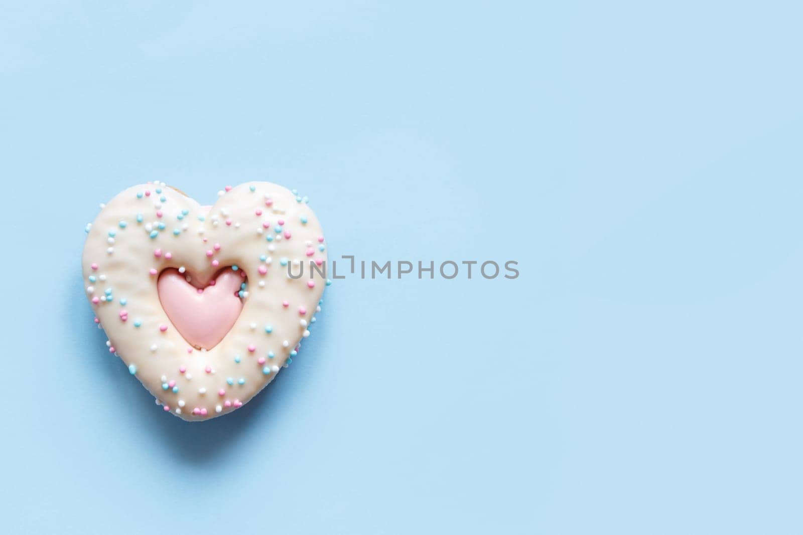 Flat lay of two heart shaped gingerbread cookies with sprinkles and icing on pink background. Top view of tasty Valentine's Day bakery, homemade bakery for romantic holiday