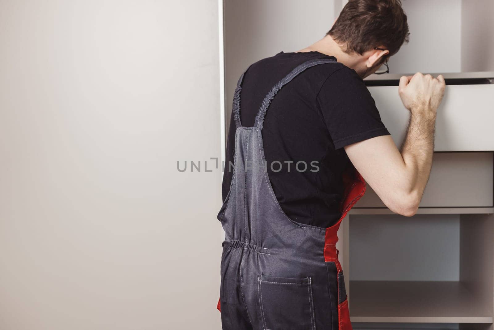 Furniture assembler installing drawers in wardrobe.