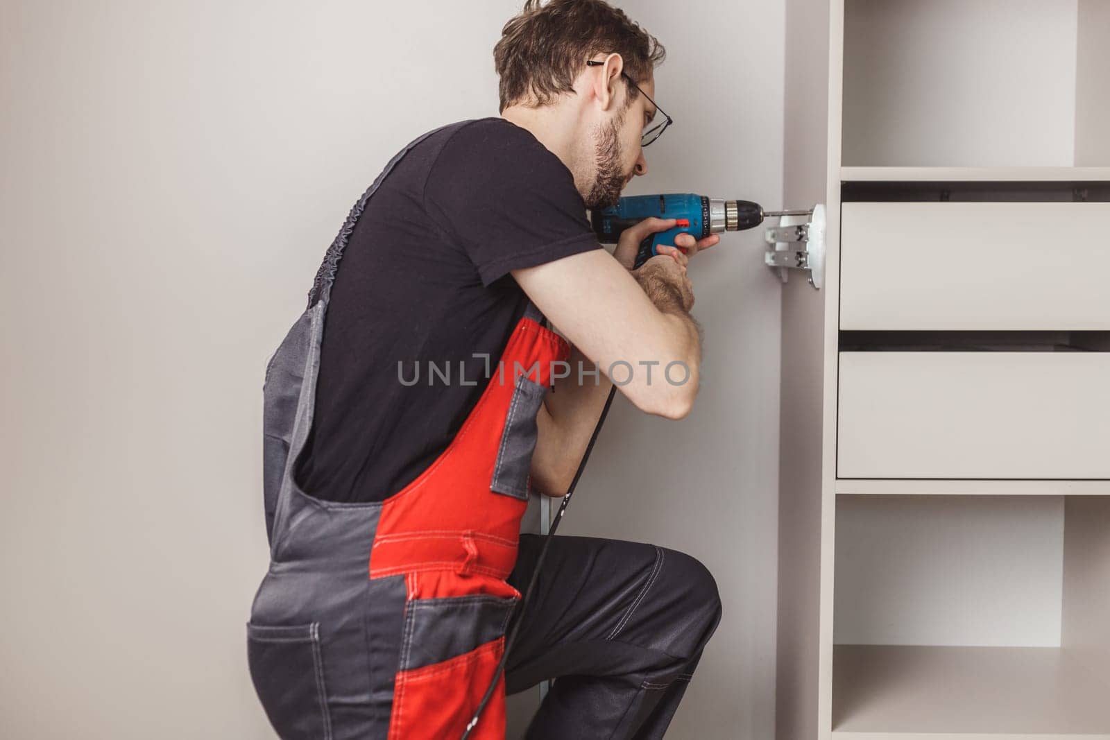 Furniture assembler drilling holes to fix sliding pants hanger in wardrobe