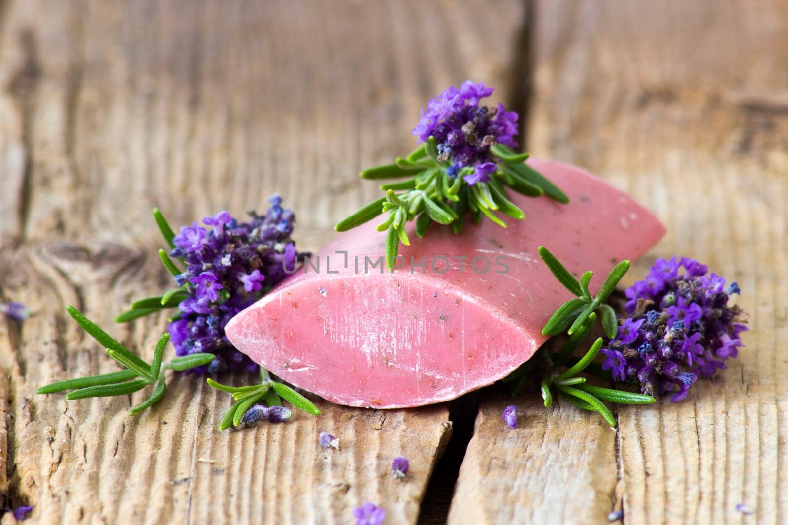 bar of natural soap, lavender flowers and rosemary on old wooden background
