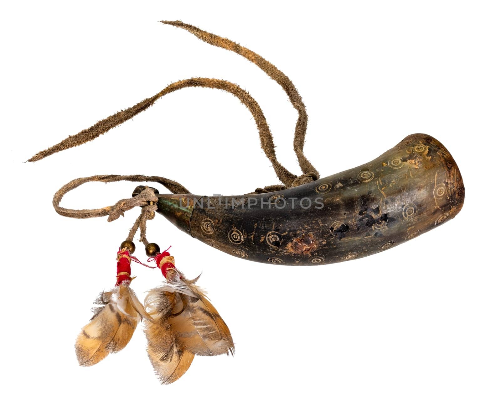 Old powder horn of the North American Indians made of horn decorated with deerskin and feathers isolated on white