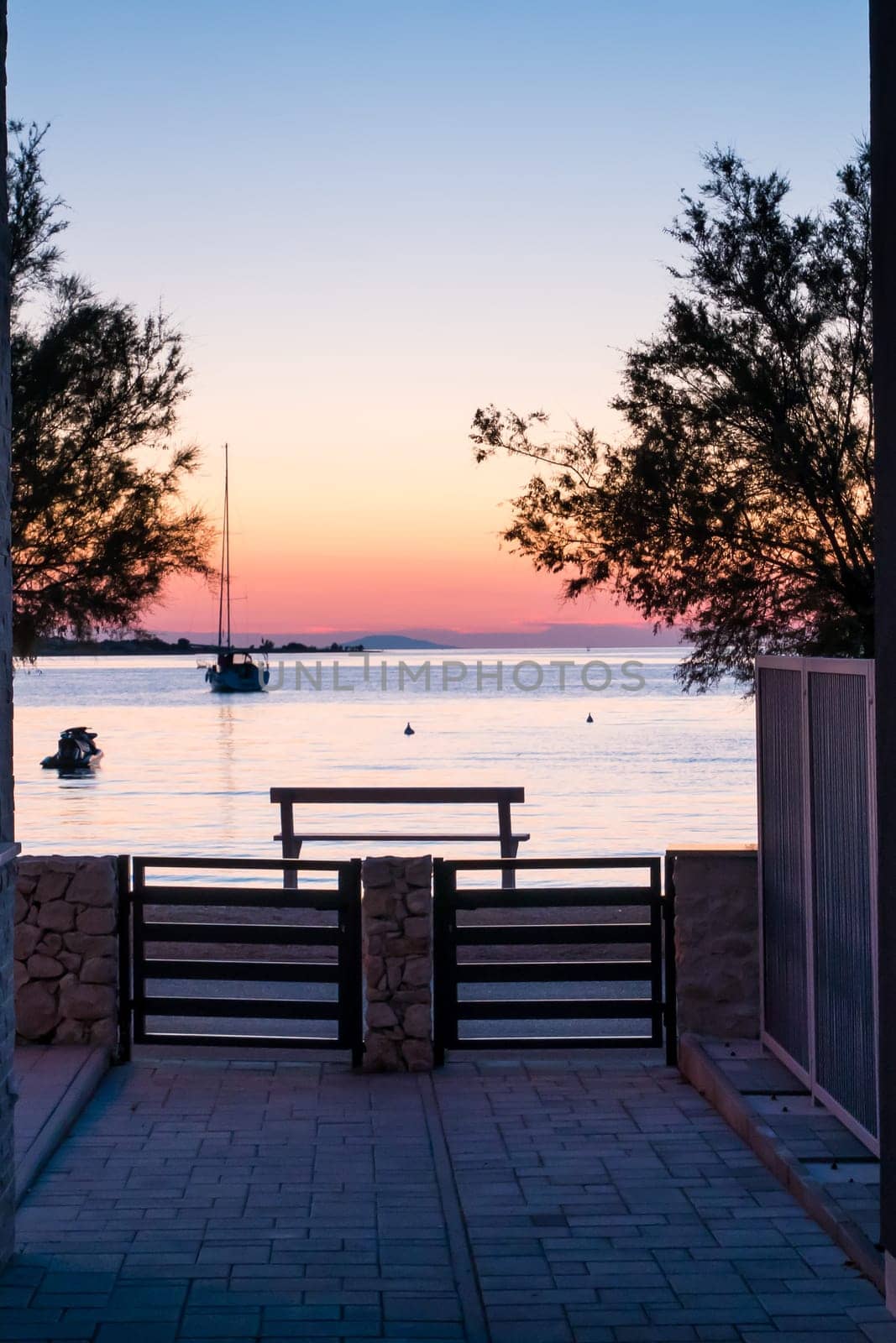 View from the yard to the sea, sailing boat and a beautiful sunset.
