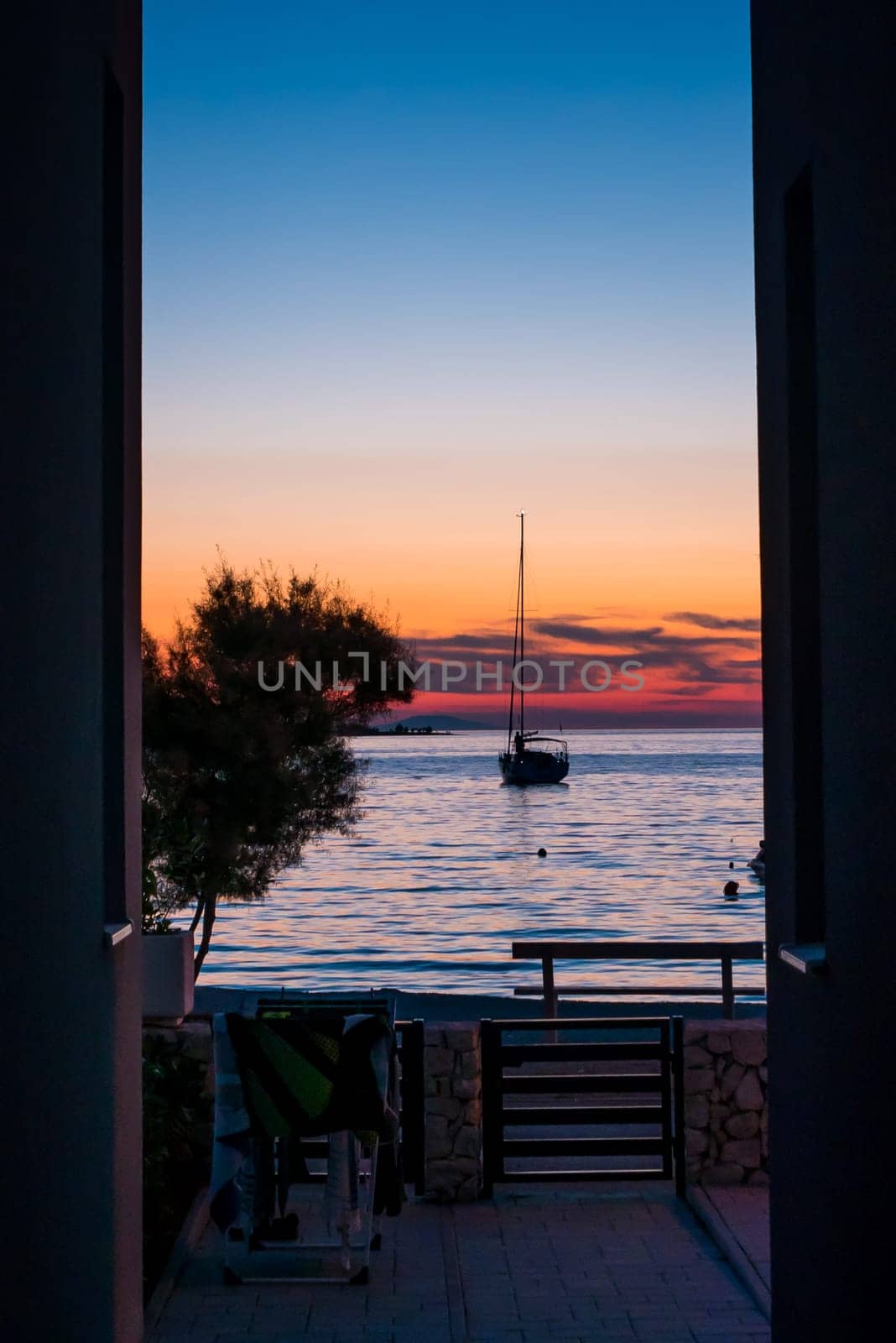 View from the yard to the sea, sailing boat and a beautiful sunset.