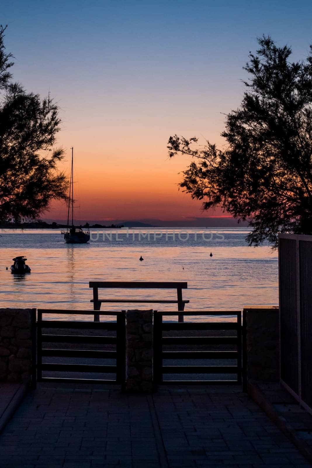 View from the yard to the sea, sailing boat and a beautiful sunset.