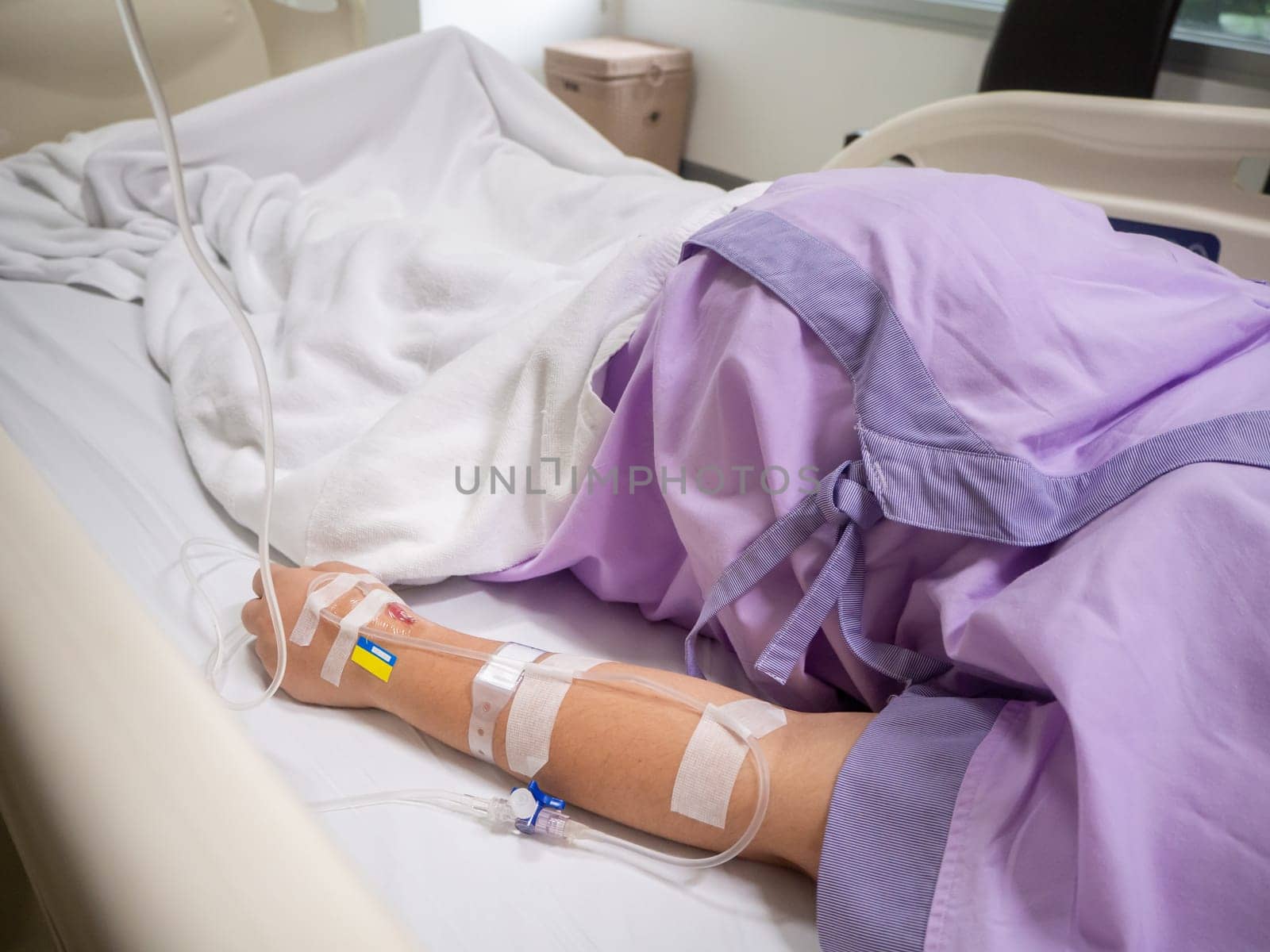 close up of saline solution on hand of women patient in pink clothes lying on the hospital bed
