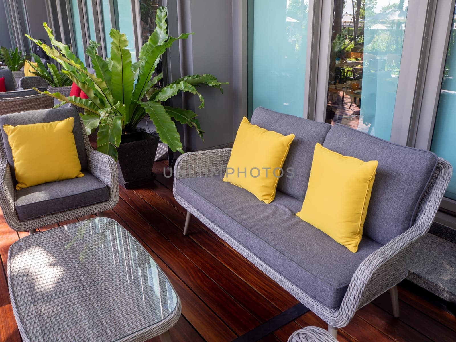 Interior photography of rattan outdoor furniture in a courtyard with garden beds and sandstone walls in the background