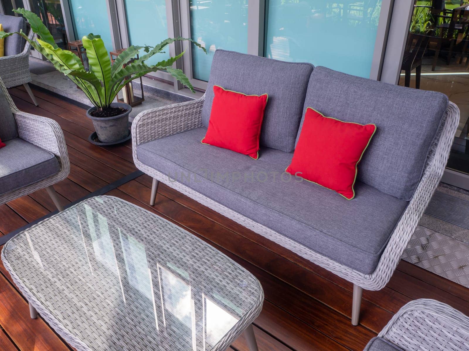 Interior photography of rattan outdoor furniture in a courtyard with garden beds and sandstone walls in the background