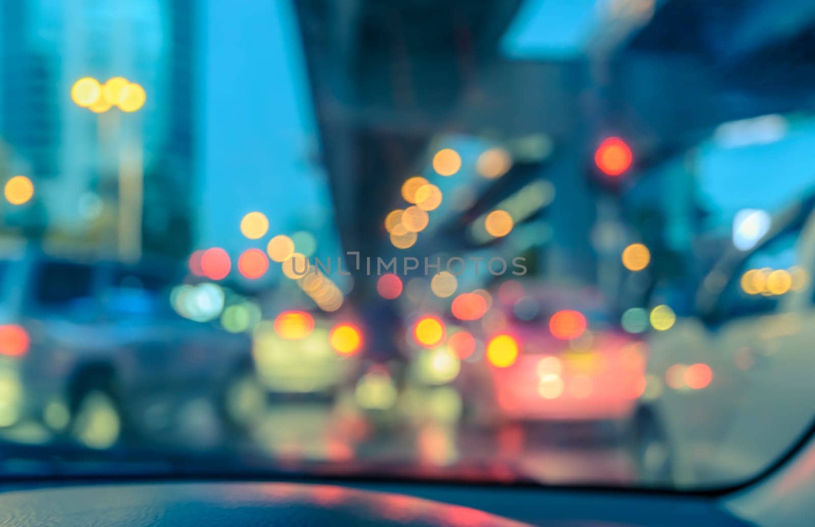 Blurred abstract background of car seen through windscreen with bokeh lights at twilight. Vintage color effect image