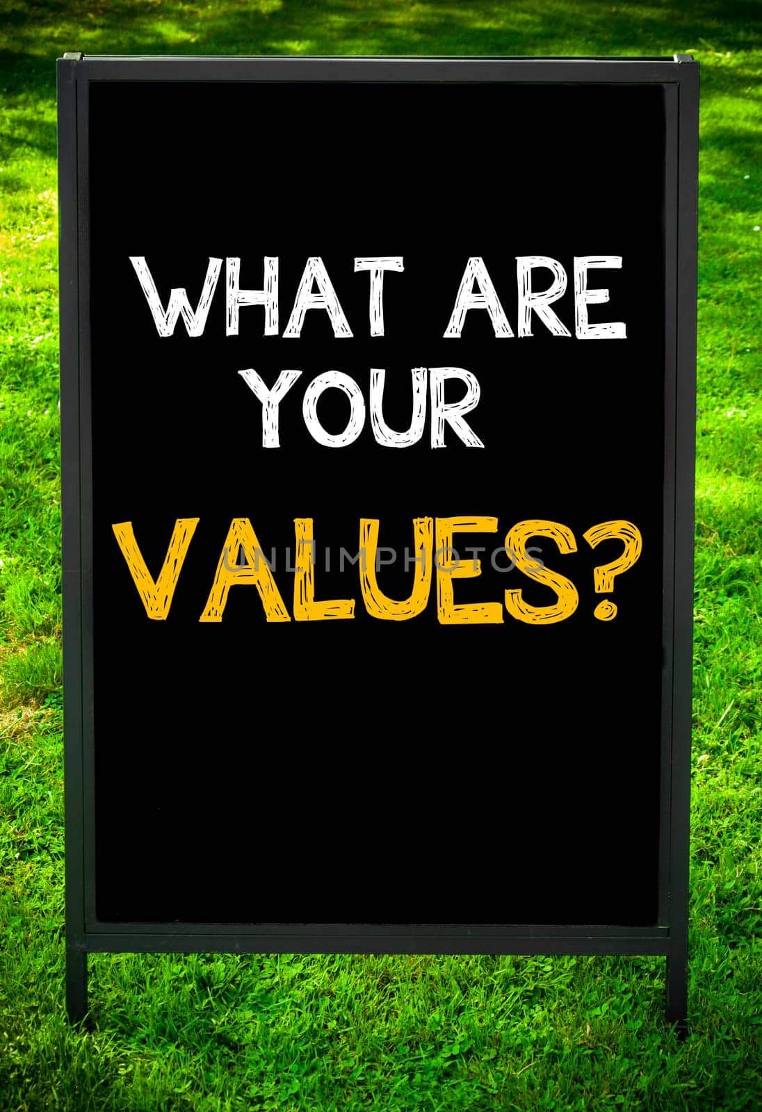 WHAT ARE YOUR VALUES?  message on sidewalk blackboard sign against green grass background. Copy Space available. Concept image