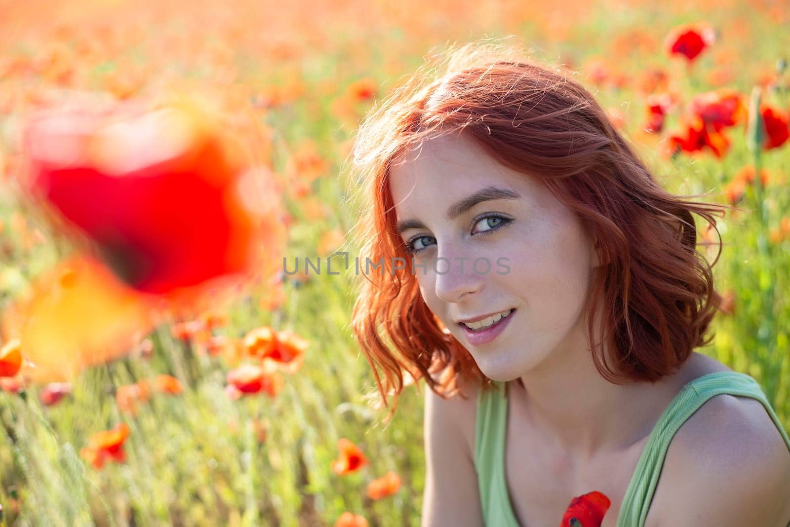 happy young girl with red hairs in poppy field