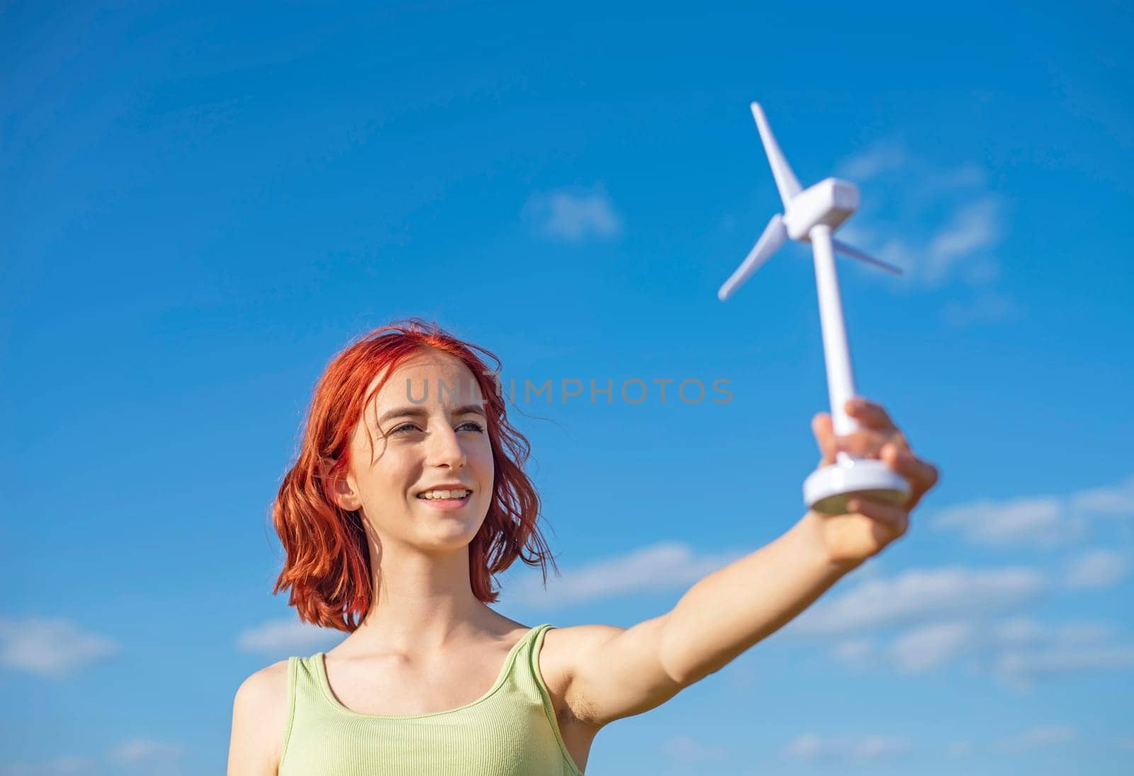 girl with wind turbine against blue sky