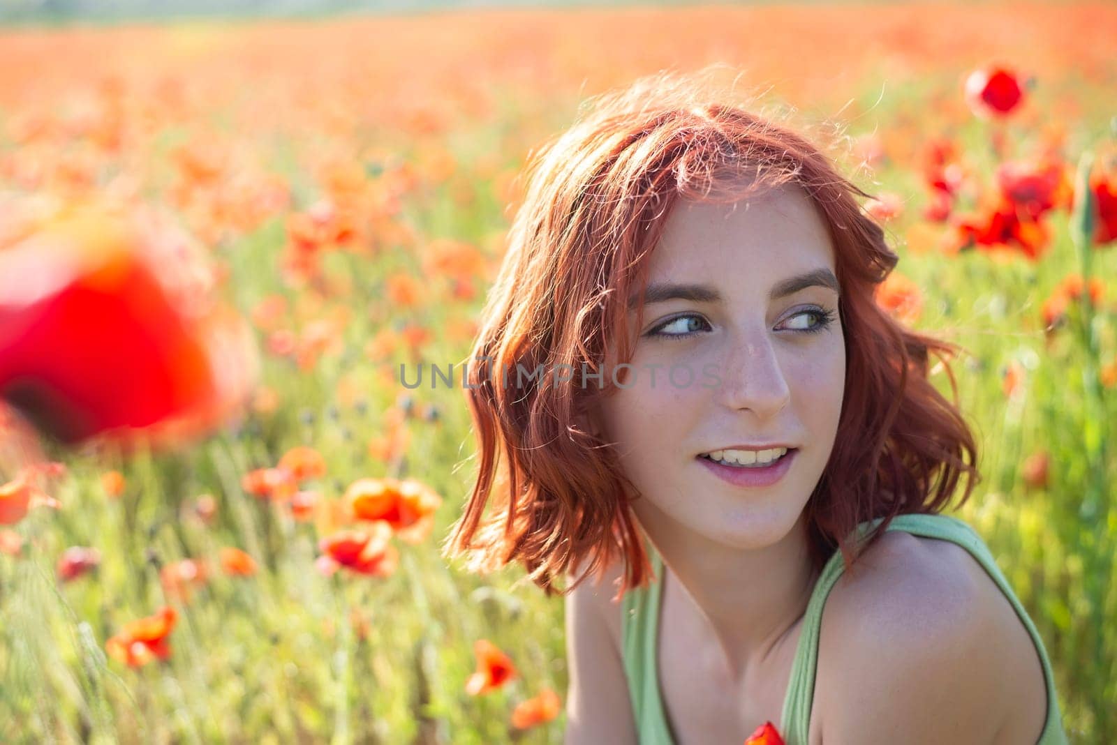happy young girl with red hairs in poppy field