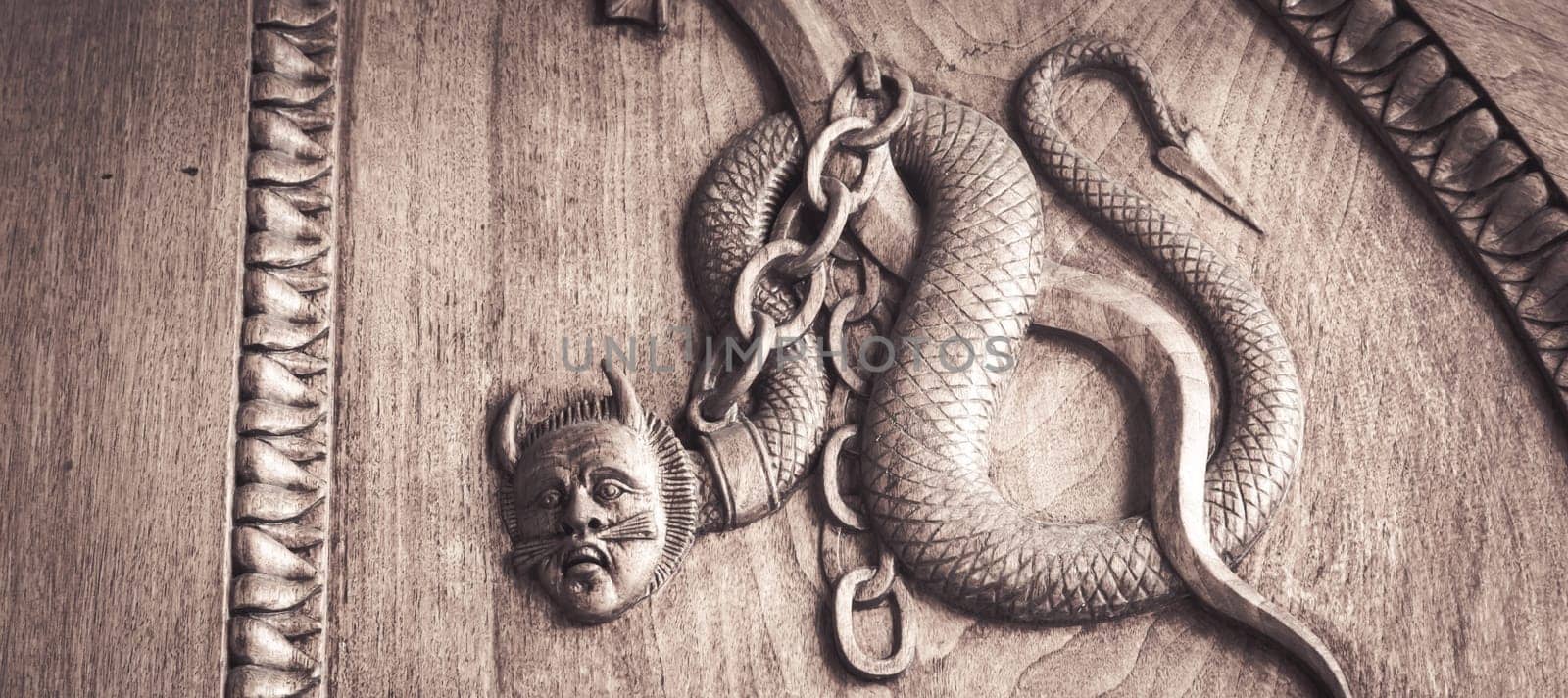 Devil snake symbol. Fantasy magic creature on an old door, 12th Century Abbey, Italy.