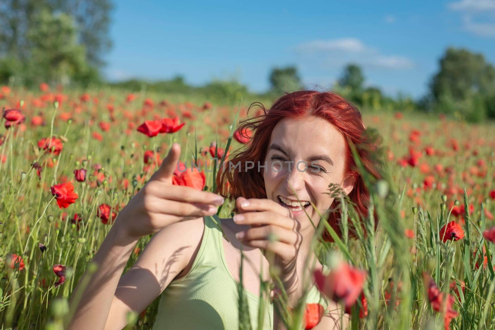 happy young girl with red hairs in poppy field
