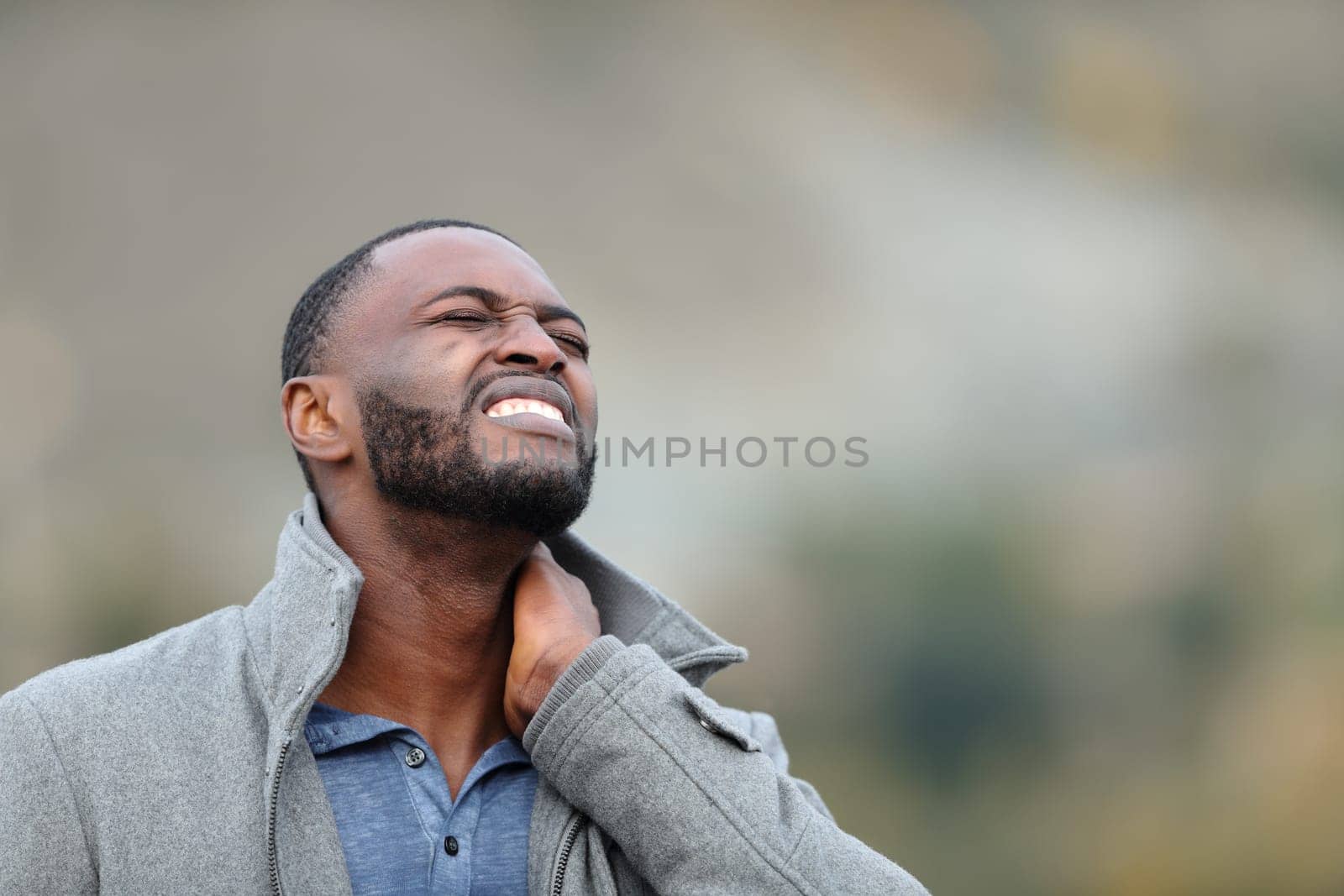 Man with black skin suffering neck ache outdoors in winter