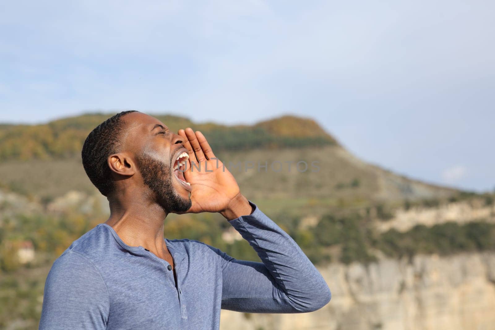 Side view portrait of a man with black skin screaming in nature