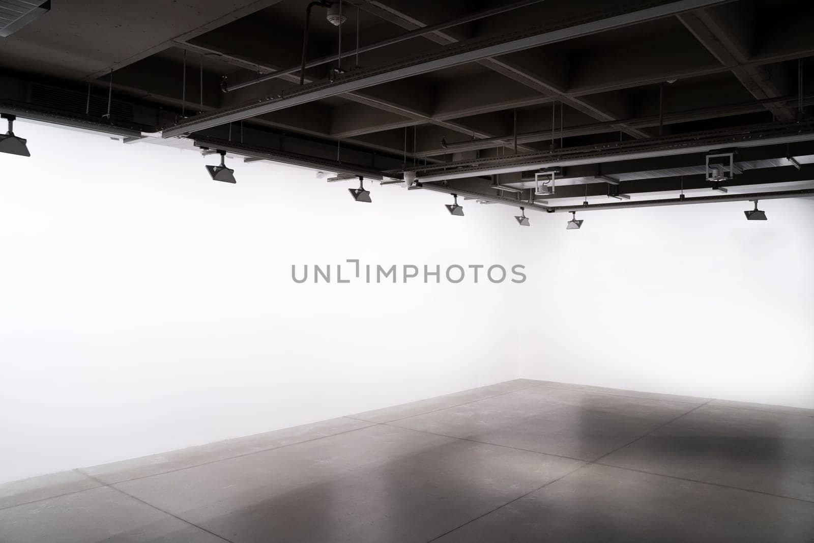 front view of exhibition industrial style interior with lights and empty white walls