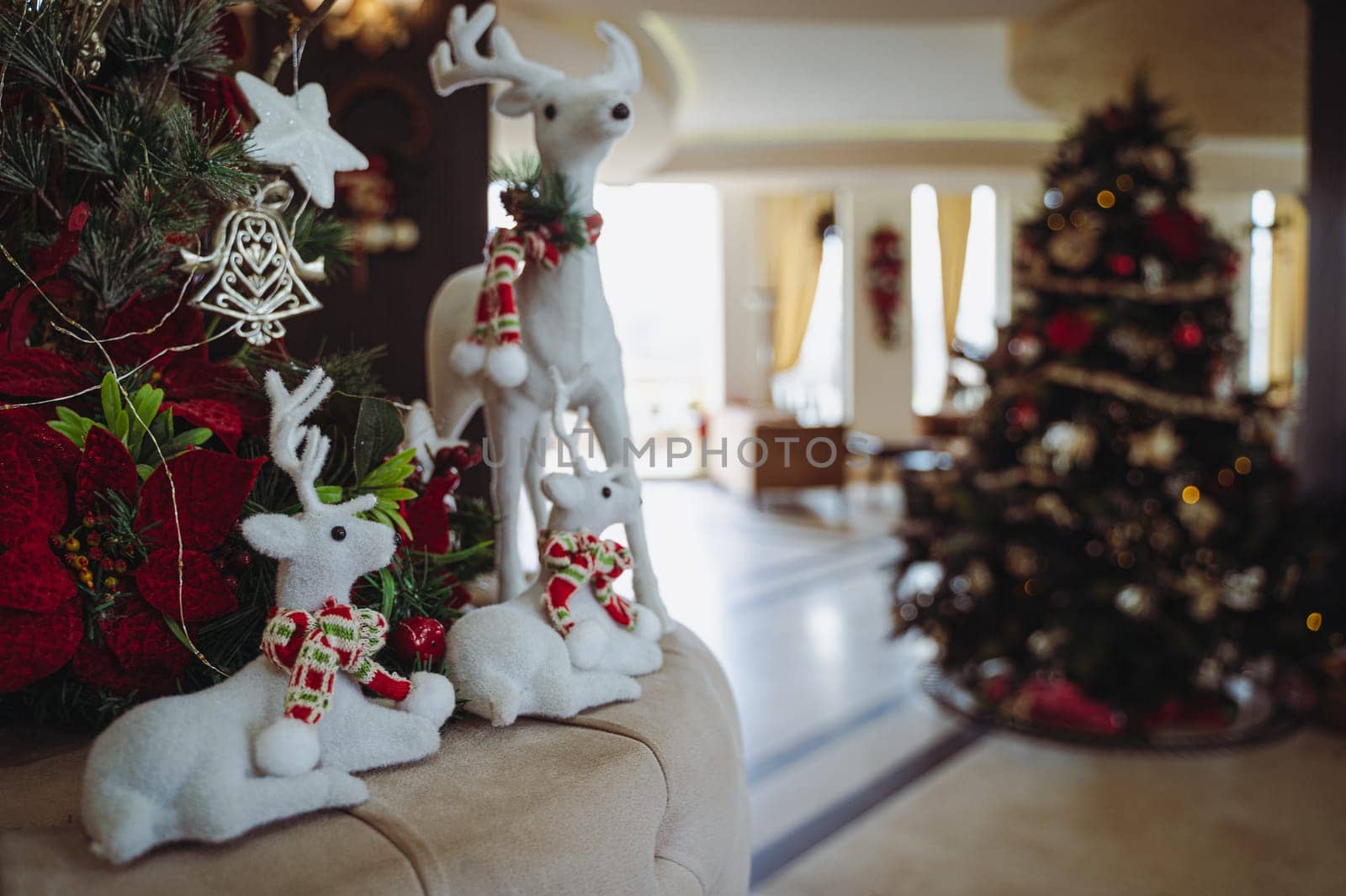 closeup front view of Christmas festive decoration with white plush textile reindeers wearing warm red scarfs and globes