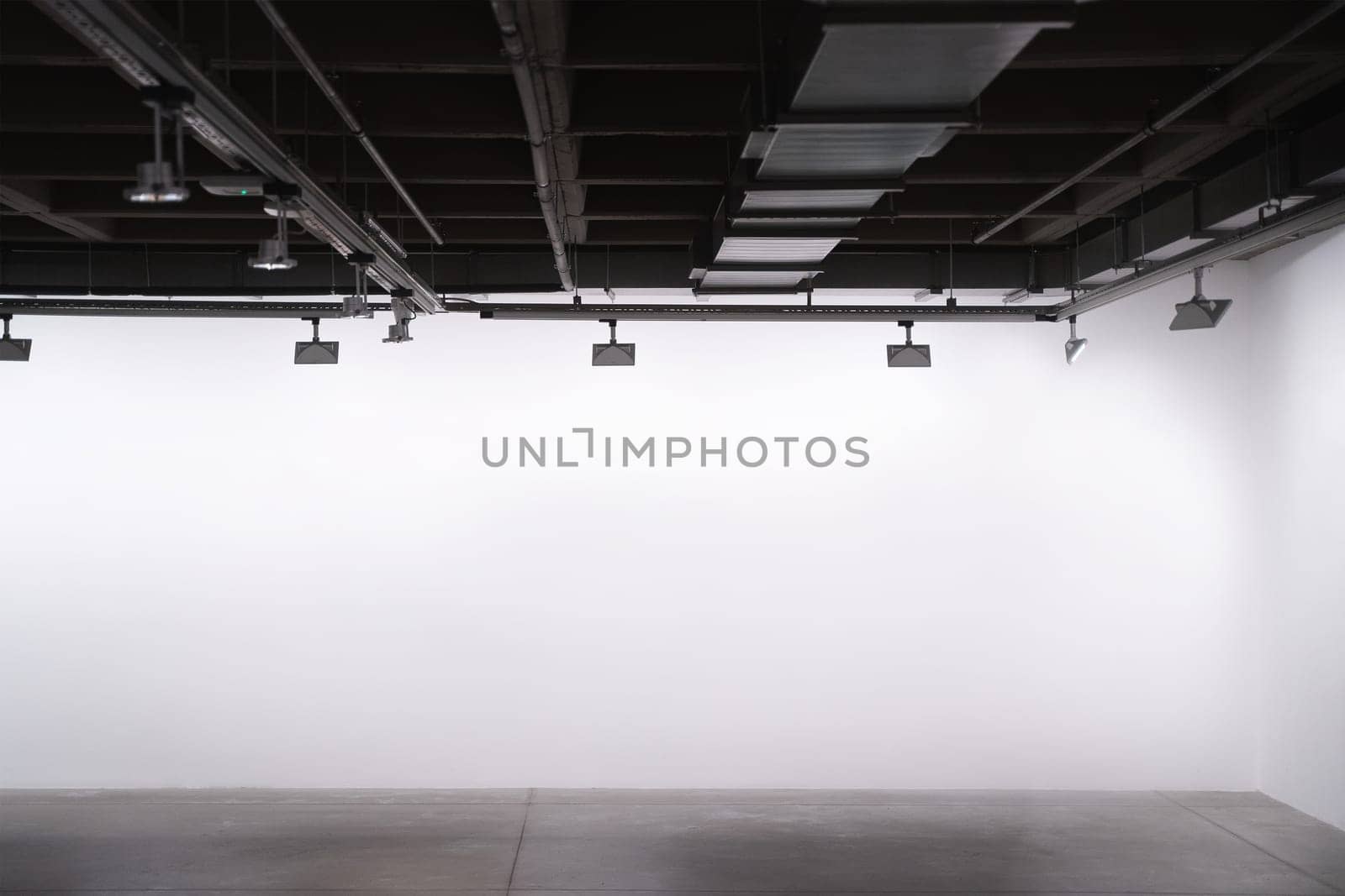 front view of exhibition industrial style interior with lights and empty white walls