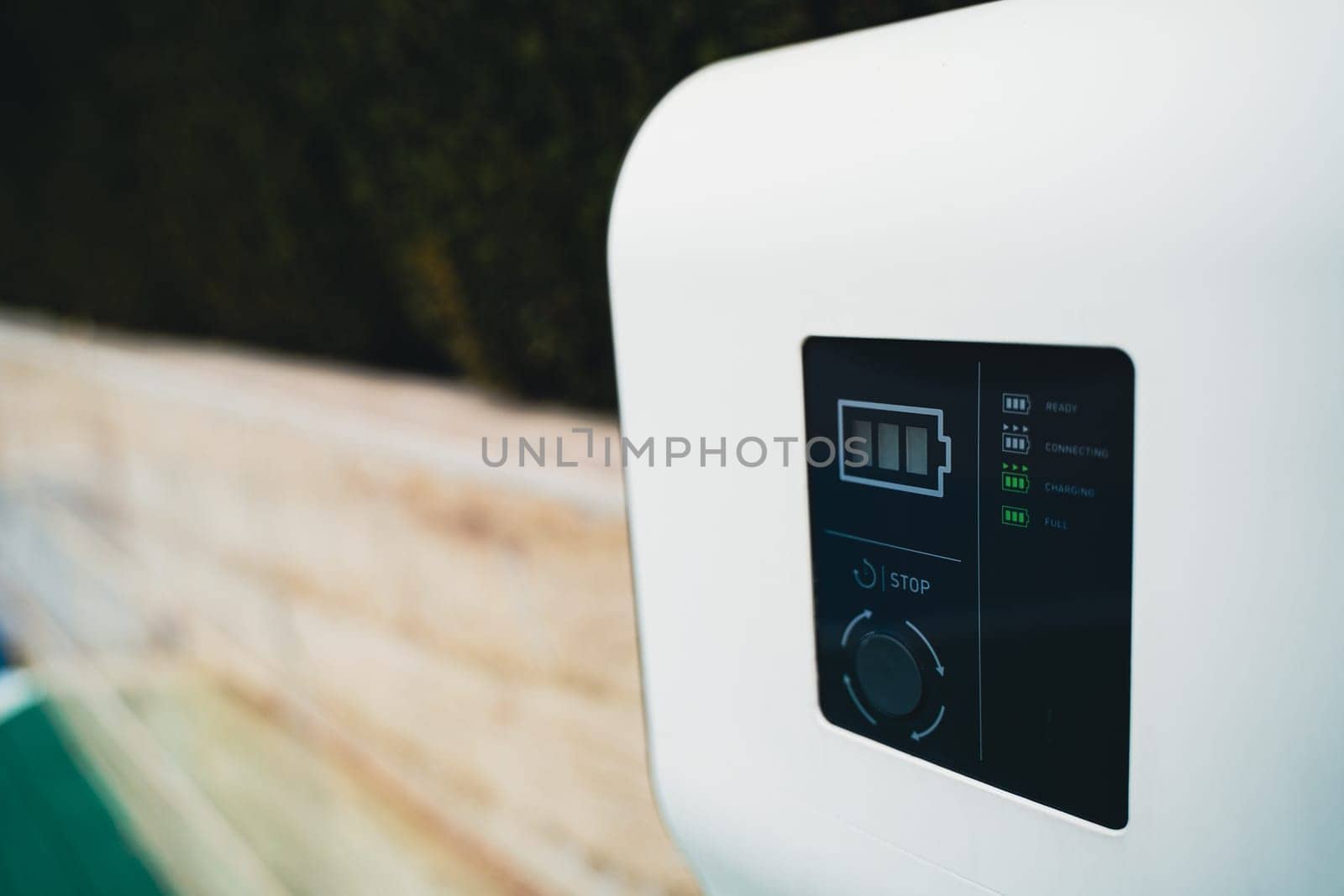 closeup perspective view of information screen of electric car charger near a stone wall in parking lot
