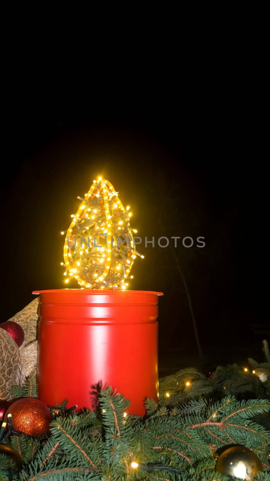 A large Advent candle made from a bucket. Christmas decoration on black background. Christmas atmosphere. An atmosphere of love, hope, peace, joy.
