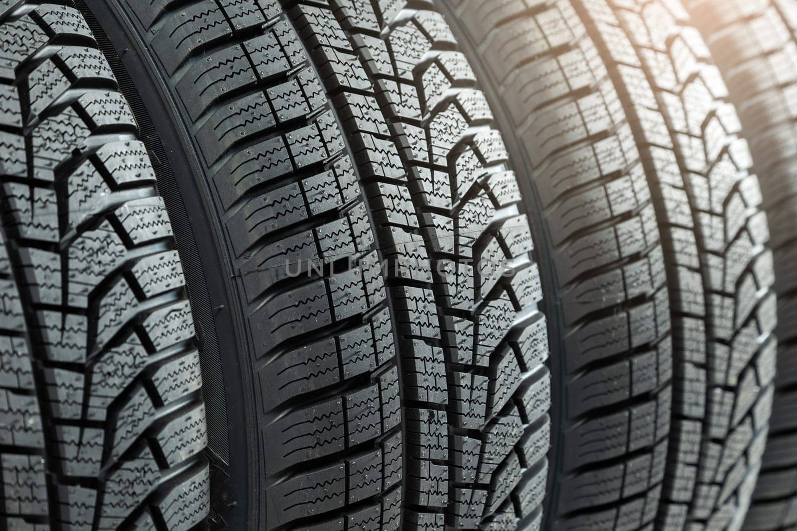 Detail of new winter tires for car with deep rubber patter to increase adhesion. Set of unused vehicle wheels for use in snow and on ice. Concept of safety on roads.